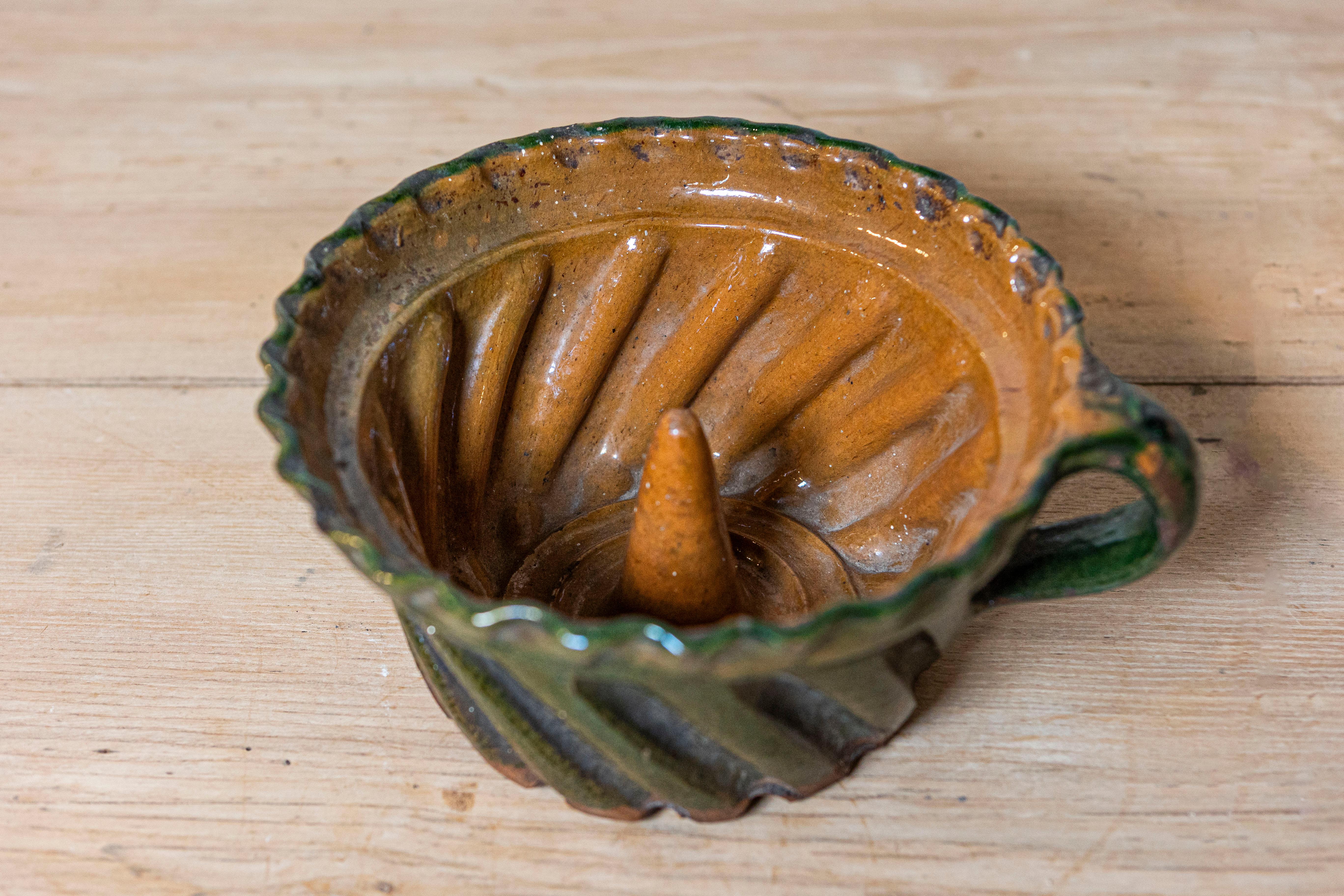 A rustic French pottery cake mold from the 19th century with green glaze. Delight in the antique charm of this 19th century French pottery cake mold. With its rustic allure and charmingly antiquated design, this piece encapsulates the beauty of
