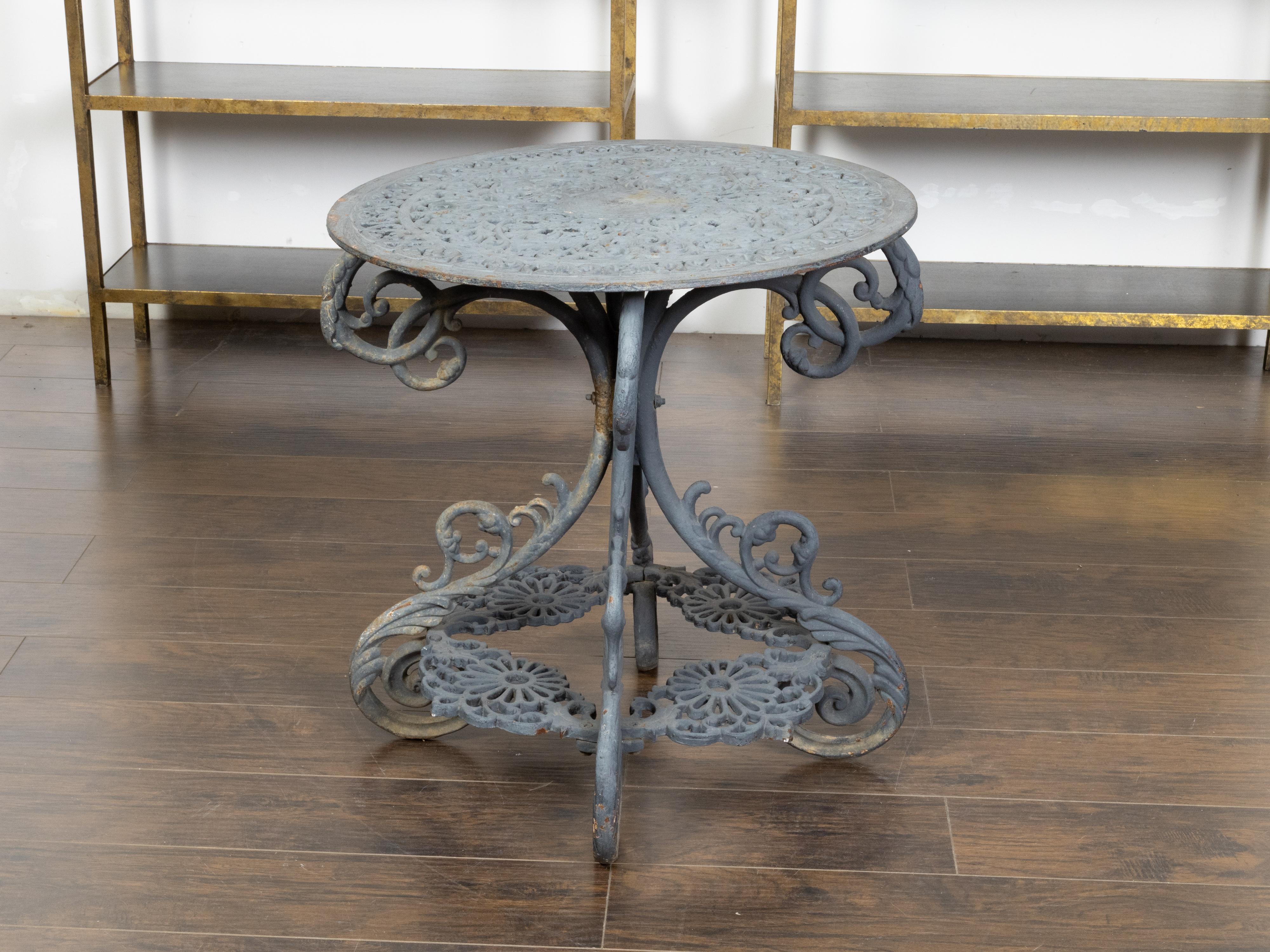 A French grey painted iron garden table from the 19th century, with foliage-themed openwork top, large scrolling legs, acanthus leaves and floral motifs. Created in France during the 19th century, this garden table features a circular top adorned