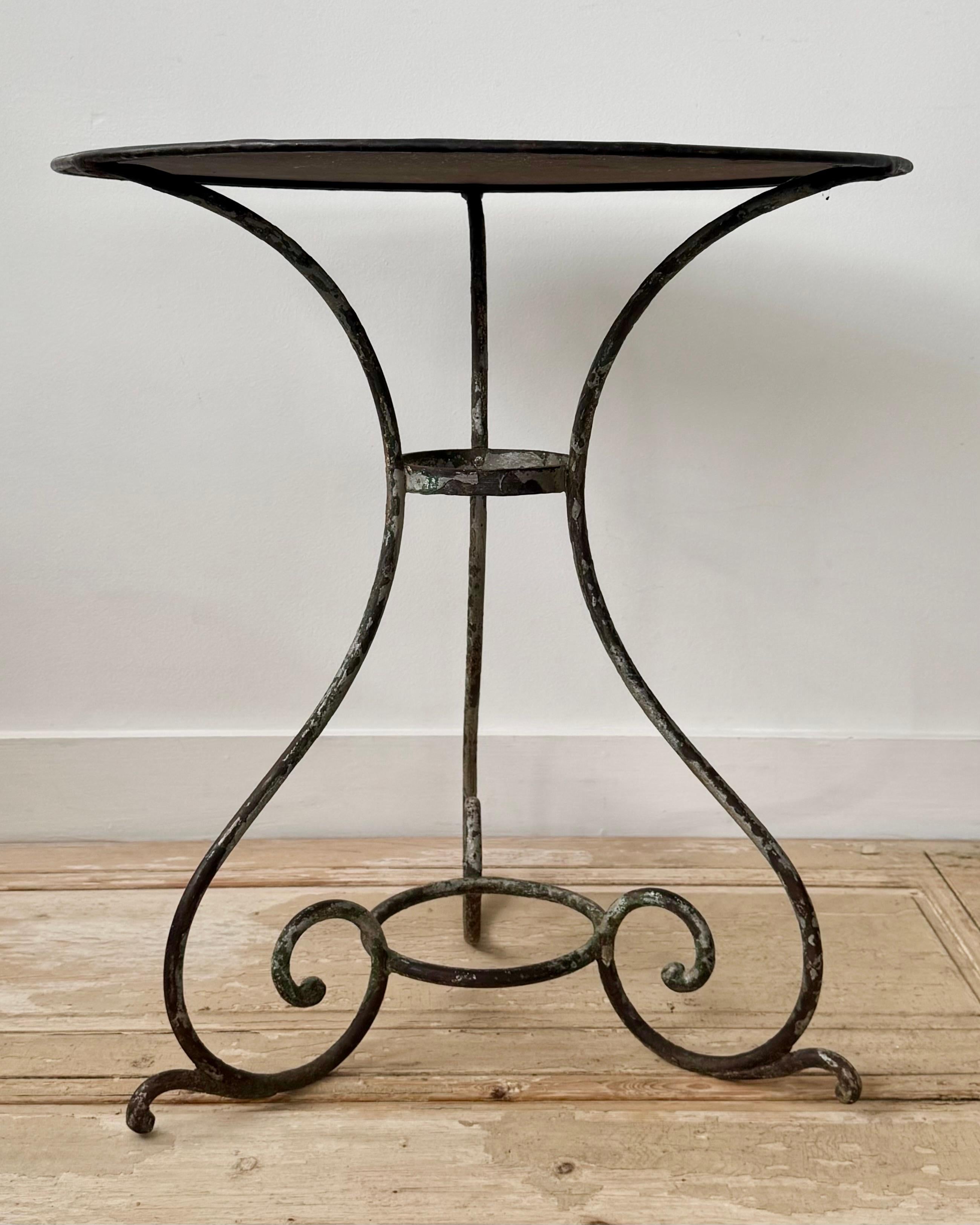 19th century French Bistro table with round top on guéridon base of tree curved legs ending in scroll feet and joined by central stretcher - all in well lived old patina.
