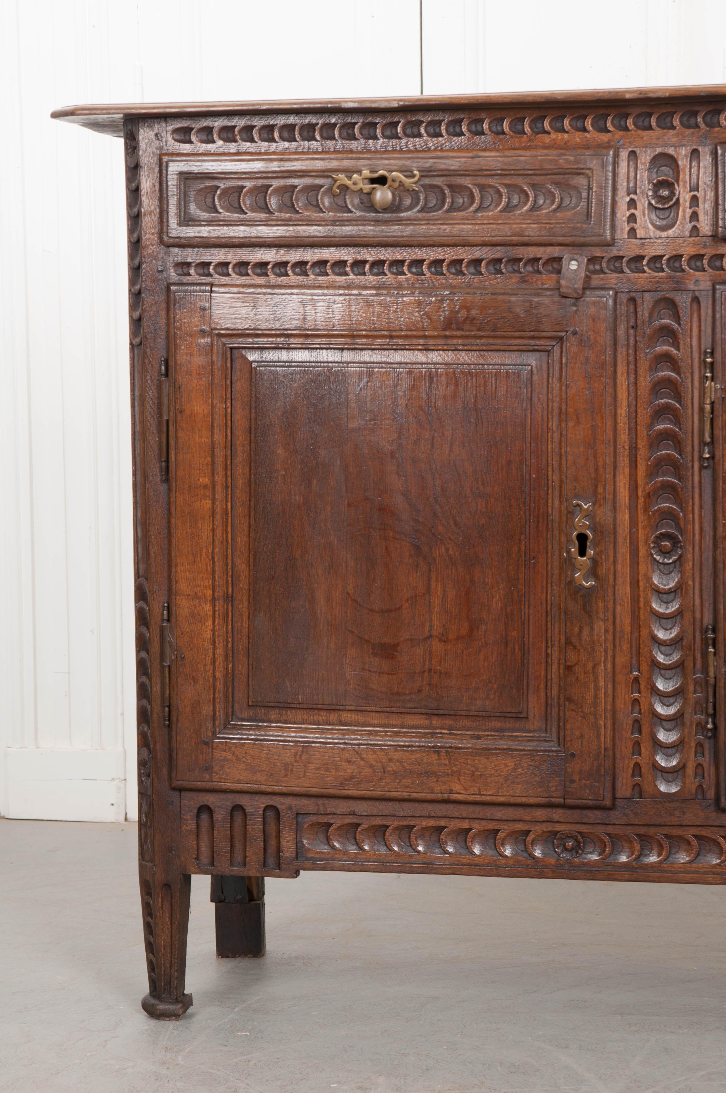 An outstanding hand carved, solid oak enfilade, made in France circa 1860. The large case piece has been meticulously hand carved with a running crescent moon motif found all-over the enfilade. Three drawers provide places for storing silverware or