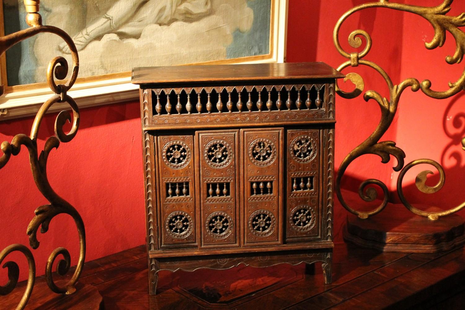 This lovely French late 19th century walnut miniature chest is ornately hand carved with the typical Coastal France, probably Breton, geometrical patterns inlays and charming hand-turned spindle design on top.
The front of this little cabinet