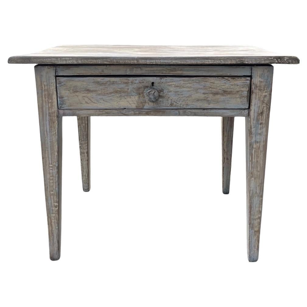 This is an example of a plain 19th Century rustic French end table with one large drawer. Over the years the paint has faded.