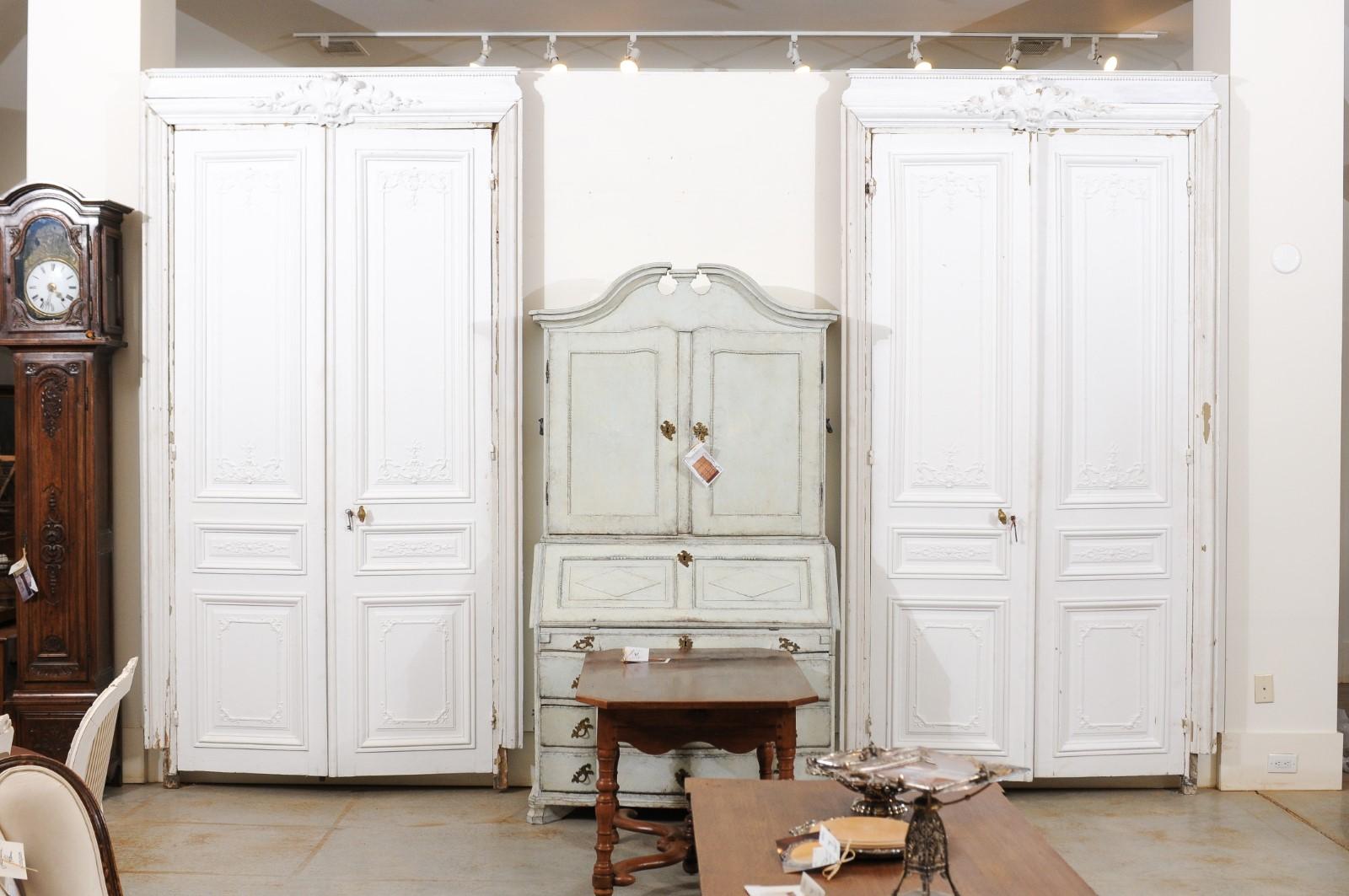 Two pairs of French Haussmannien doors from the 19th century, with carved motifs, priced and sold per pair. Created in France during the second half of the 19th century, each pair features a carved frame accented with foliage motifs on the crest,