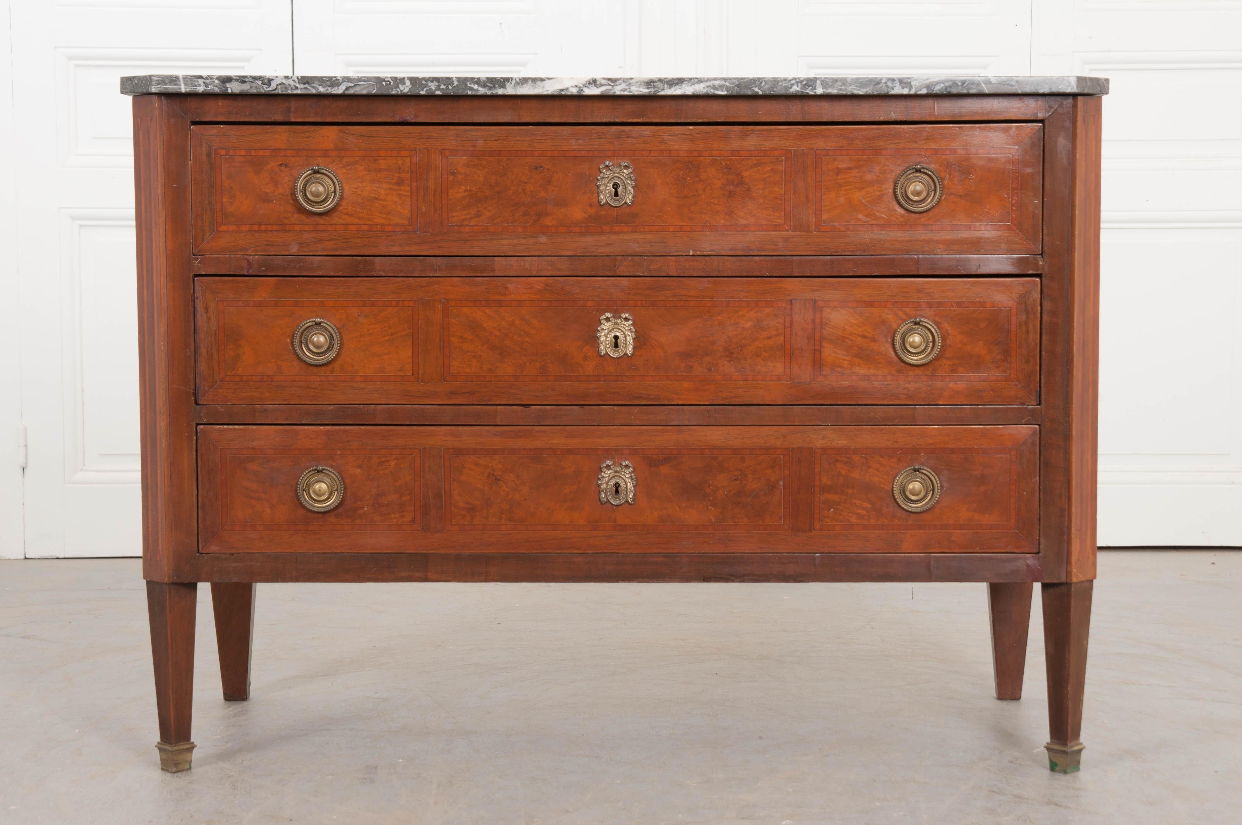 Outstanding inlay graces nearly every surface of this beautiful 19th century French Directoire style commode. The commode features a gray marble top, which is in wonderful antique condition, that has canted corners that match those on the body. The