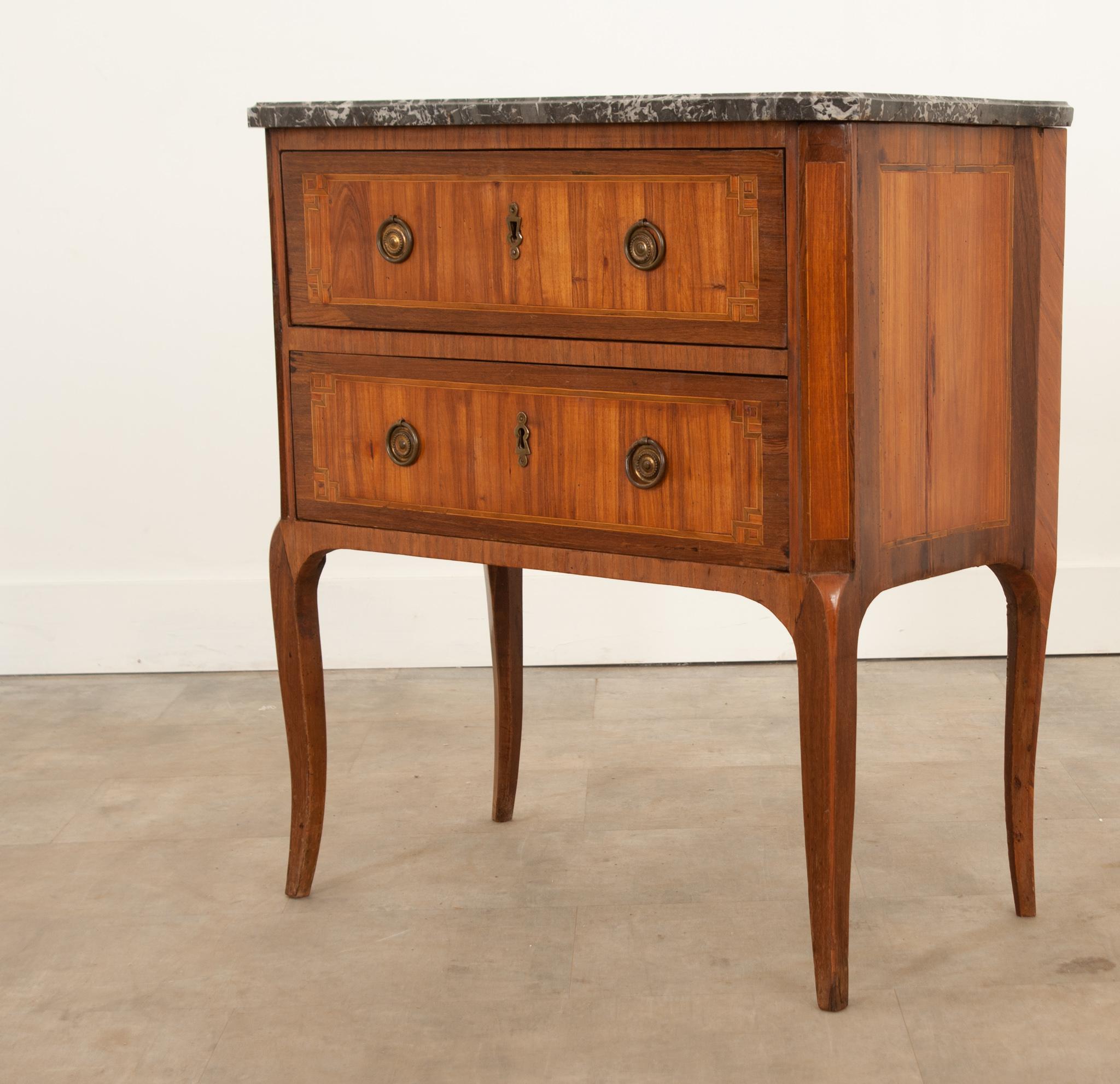 A great petite inlay commode from 19th century France. Topped with a shaped piece of marble that is removable.Canted corners and drawer fronts showcase the geometric inlay design. Cast brass drop ring pulls make it easy to open the drawers. No keys