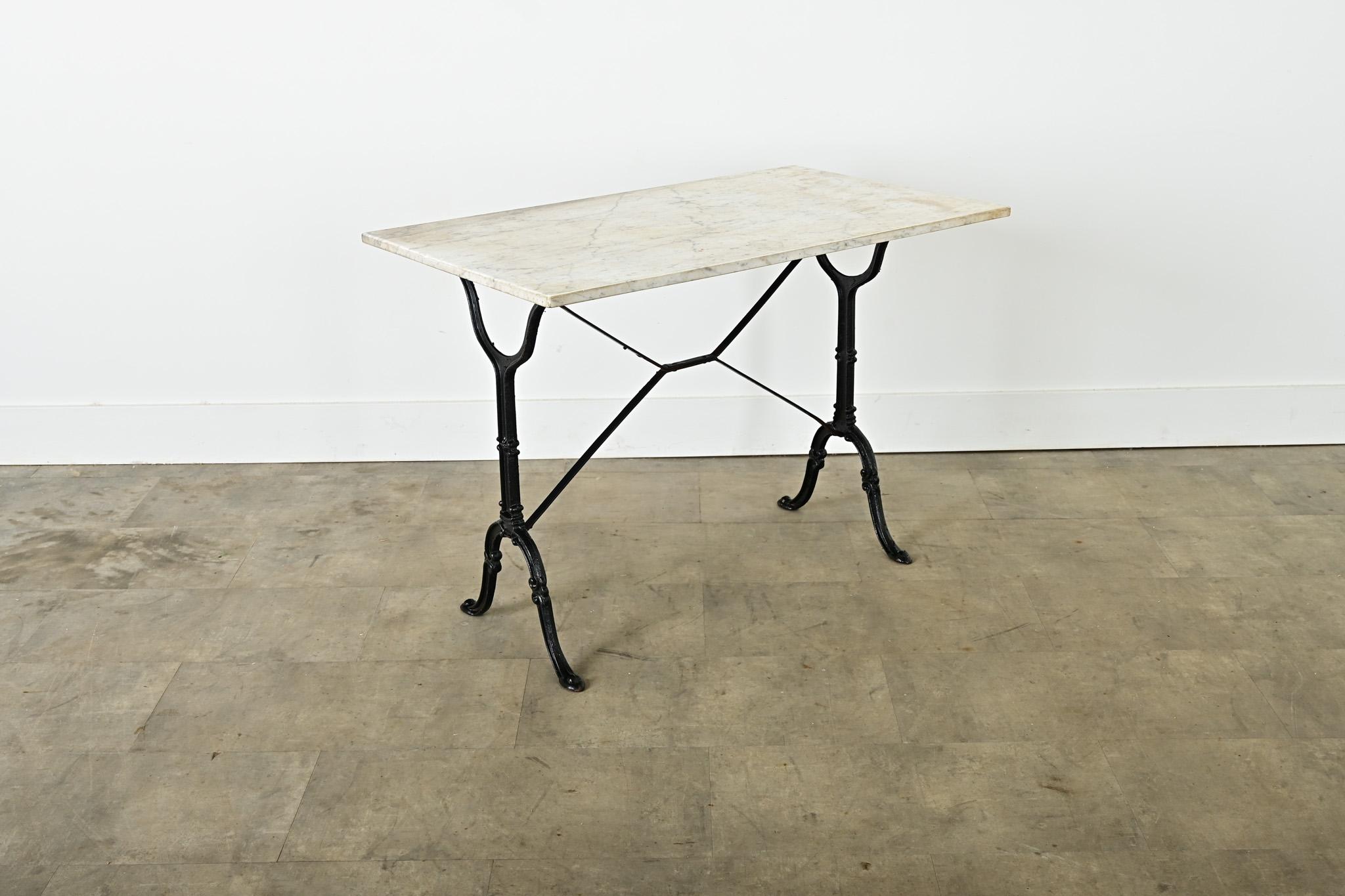 An original French brasserie table, circa 1890, with a removable white marble top on a cast iron frame. The stone top has flat edges and a smooth, although patinated surface clouded with beige discoloration. Slender iron legs of graceful, Beaux Arts