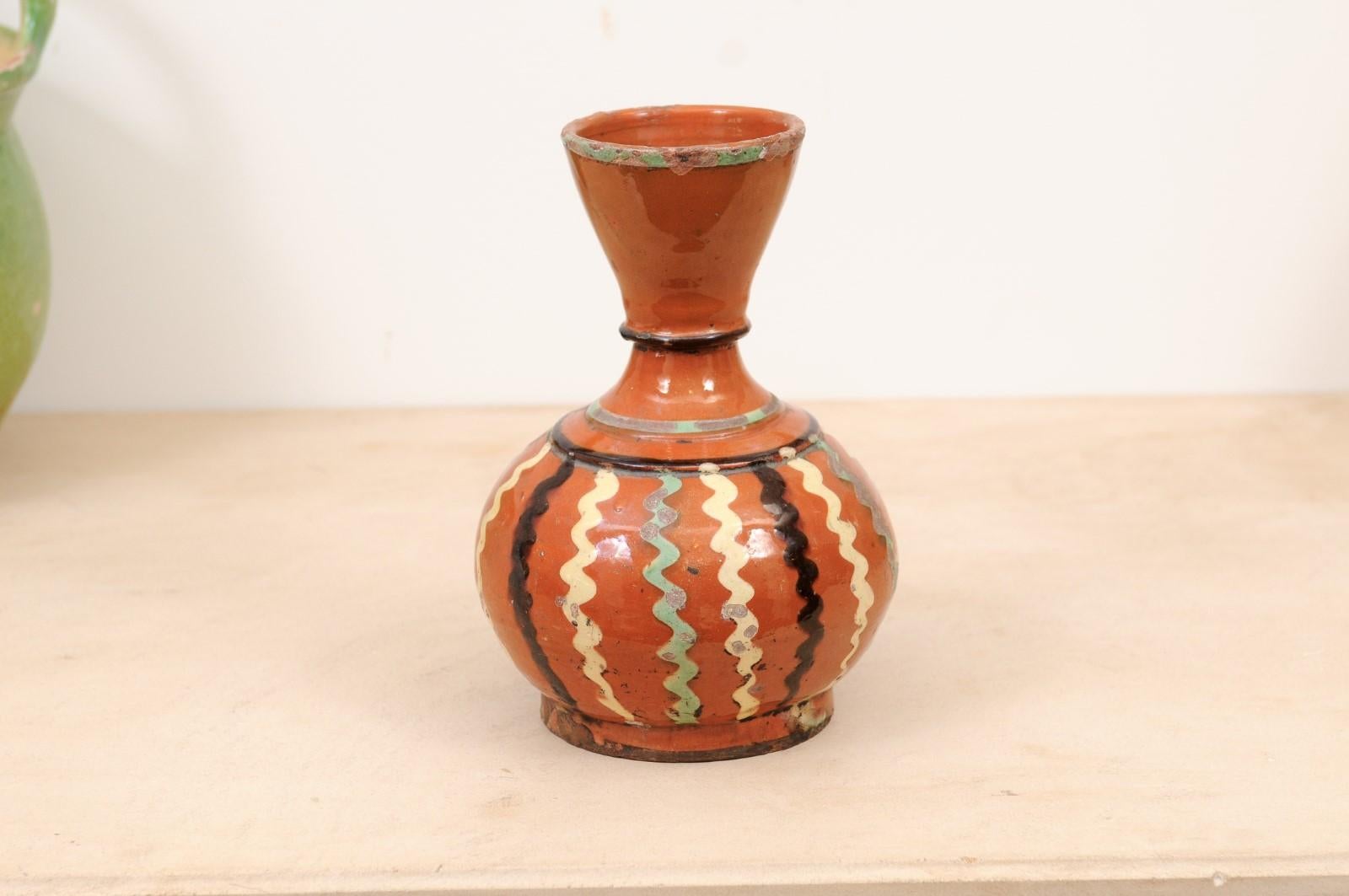 A French jaspe pottery wine serving jug from the 19th century, with rust glaze and black, cream and soft green wavy décor. Created in France during the 19th century, this wine serving jug features a rust colored ground perfectly accented with black,