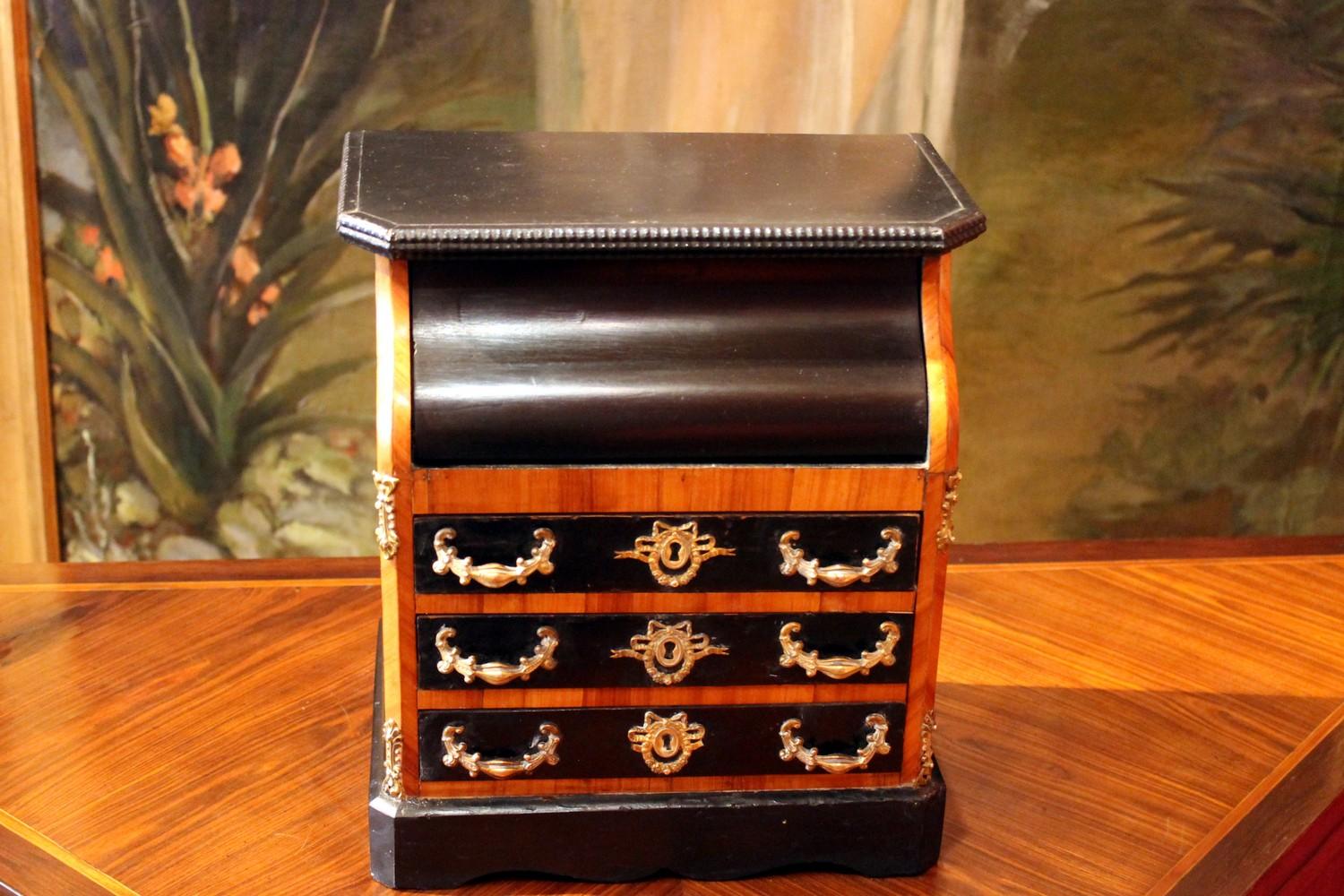 This beautiful French late 19th century chest of drawers in black ebonized wood and cherrywood reproduces with perfect proportions in scale a miniature cabinet with three drawers and an upper flap door that opens to reveal a white marble top and an