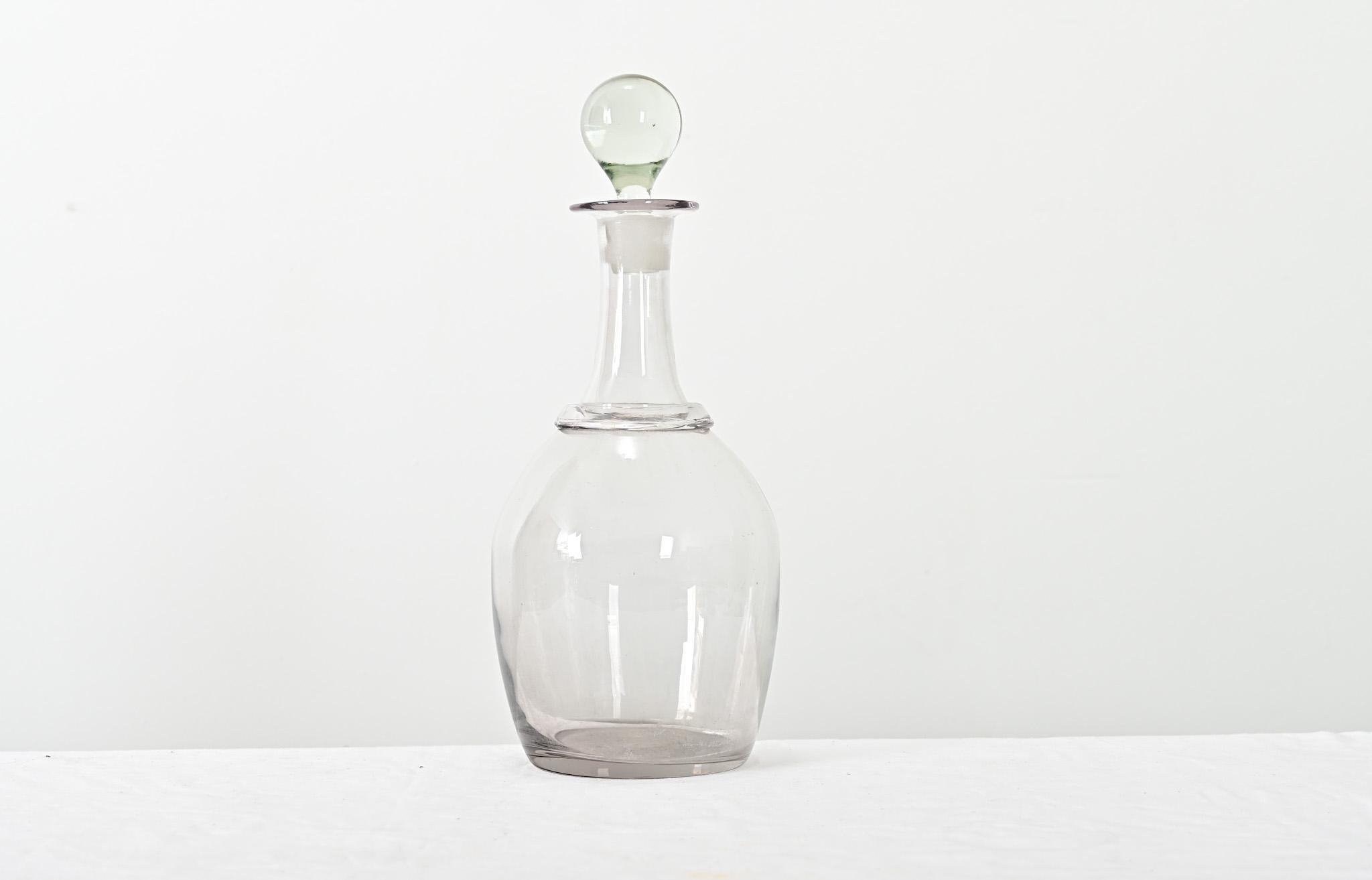 Encantador decantador de vidrio soplado, hecho a mano, del siglo XIX, procedente de Basse, en la Baja Normandía, donde las manzanas de Calvados se convierten en aguardiente. El tapón es un sólido orbe de cristal que encaja en el esbelto cuello que