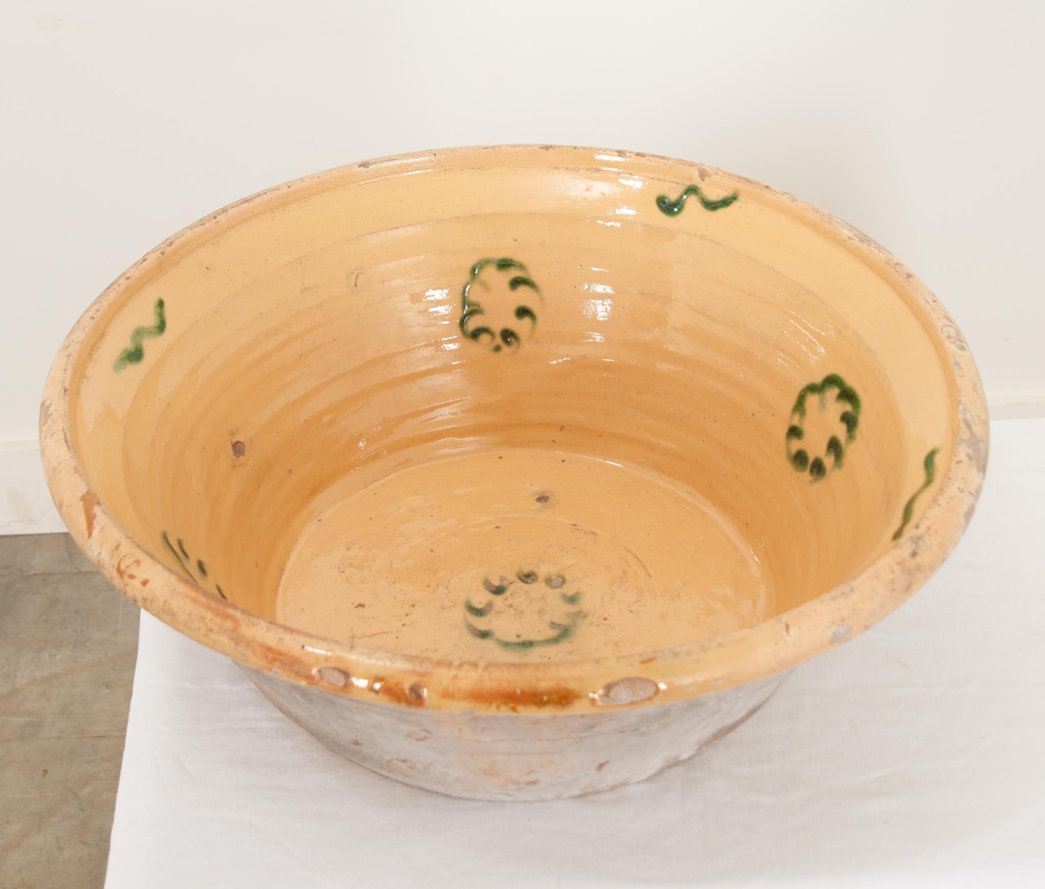 A fine mixing bowl made during the 1850’s in France. The bowl has been glazed with a rich, glossy yellow and whimsical green floral form on the interior. This beautiful example of antique kitchenalia will make a wonderful centerpiece for your dining