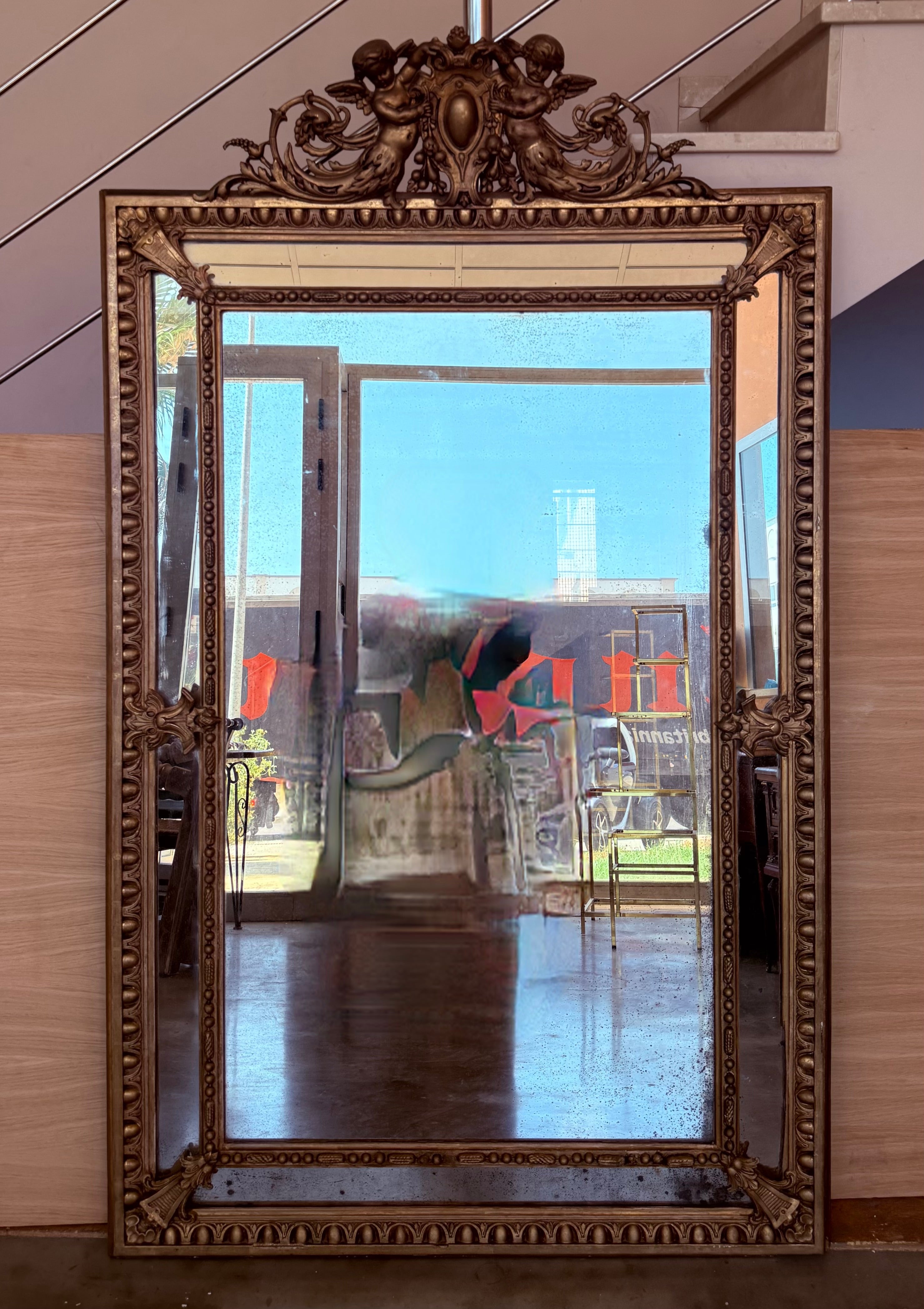 An exceptional large scale mirror hand-crafted in France, this piece is vertical symmetrical and the original mirror plate sparkles with diamond dust.. This mirror is beautiful and features an exquisitely carved repeating Neoclassical design around