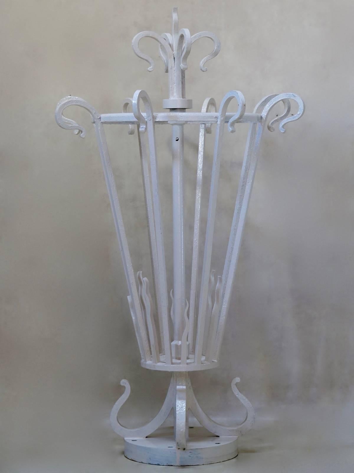 Tall and elegant wrought iron lantern, originally designed to be placed atop a masonry column. Very heavy. The base is pierced with holes to secure into place. Topped with stylized fleur-de-lys finials. The central shaft is hollow, to thread wiring
