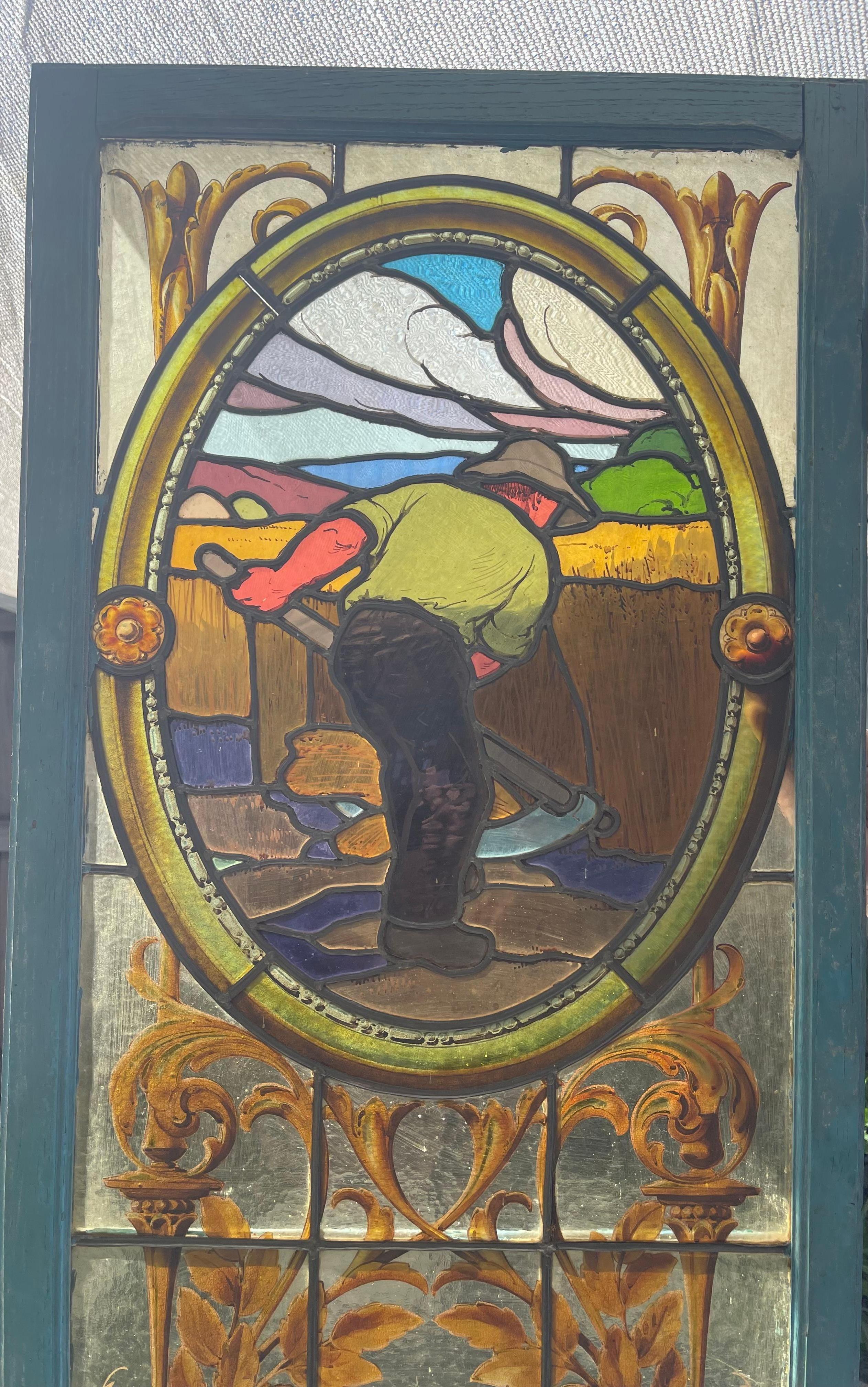 Beautiful old stained glass window from 1890 representing a countryside scene. At its base a work of glass in the form of a shell reveals a vase and its acanthus leaves. On the top of the panel, a man harvesting wheat, all made of different colored