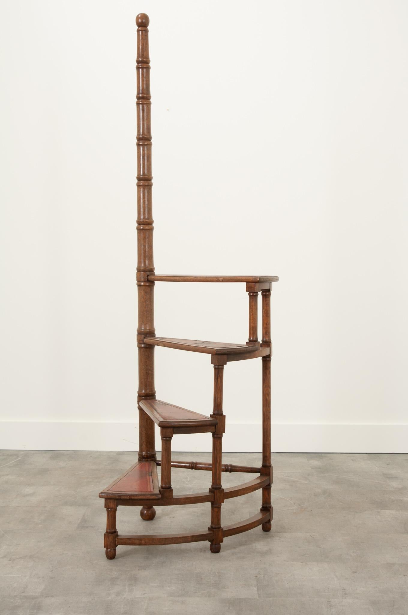 This French 19th century library step ladder is the perfect functional antique to elevate any space. The semi-circular ladder features four stairs rolled around a turned central post. The bright red toned leather with gold tooling inset into each