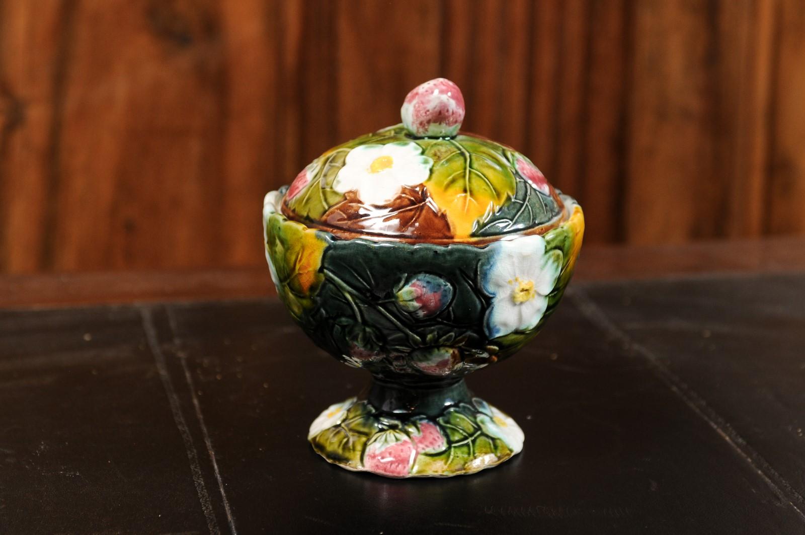 A French majolica lidded bowl from the 19th century, with strawberry motif, white flowers and foliage. Created in France during the 19th century, this bowl features a circular lid accented with a strawberry-themed handle and adorned with delicate