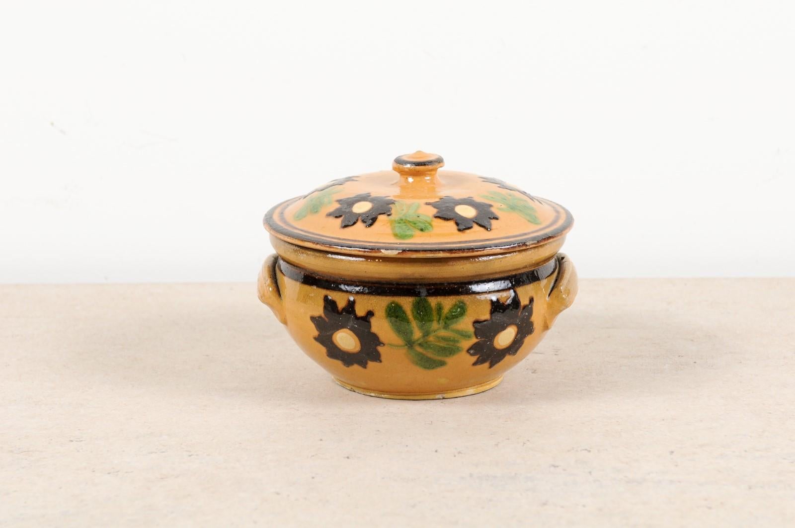 A French lidded pottery bowl from the 19th century, with floral decor. Crafted in France during the 19th century, this pottery bowl charms us with its contrasting colors and unpretentious decor. Showcasing a lid decorated, along with the rest of the