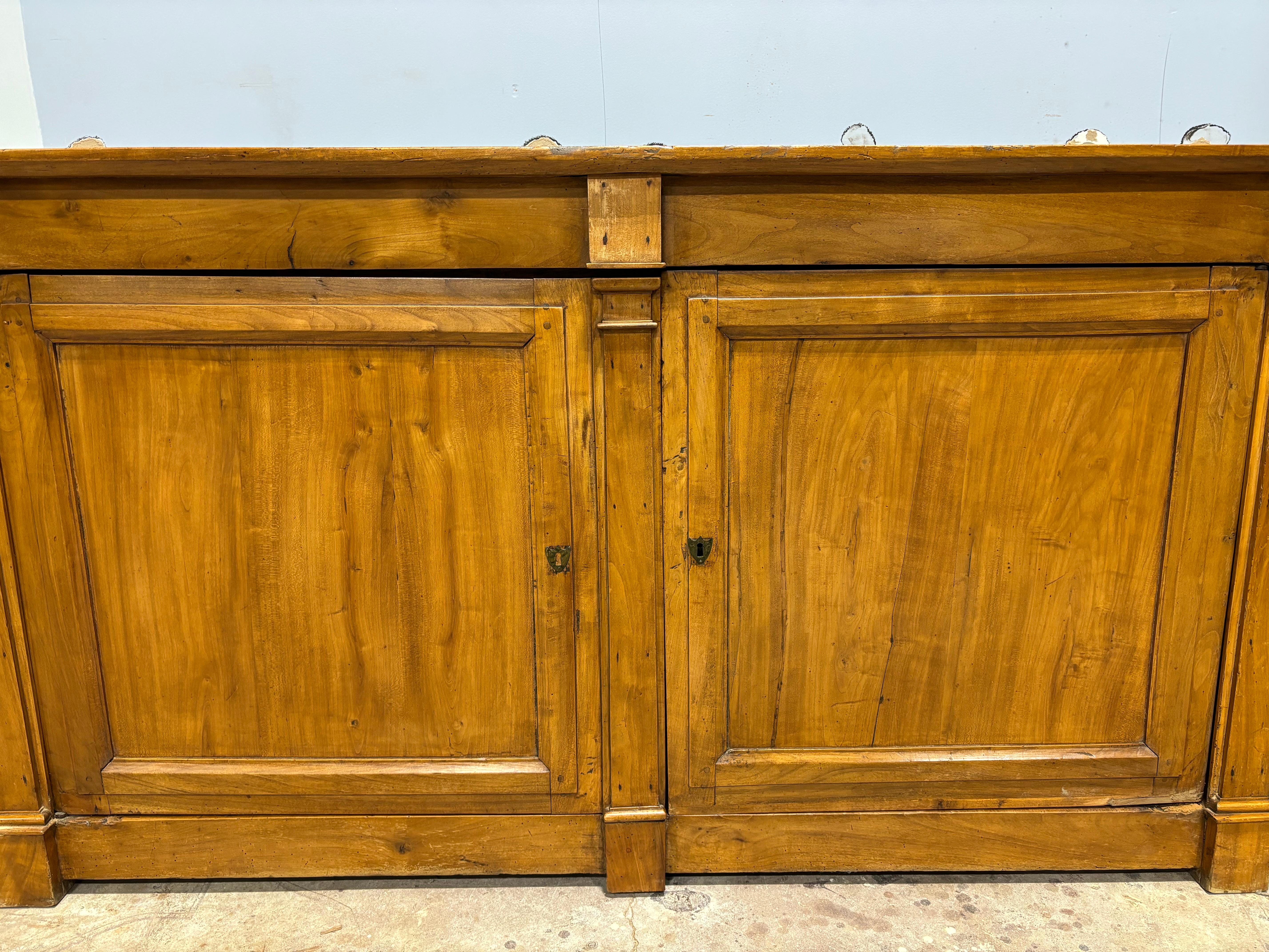 This is a long buffet, close to the size of a sideboard. It has 3 flat columns. The wood is blond walnut.