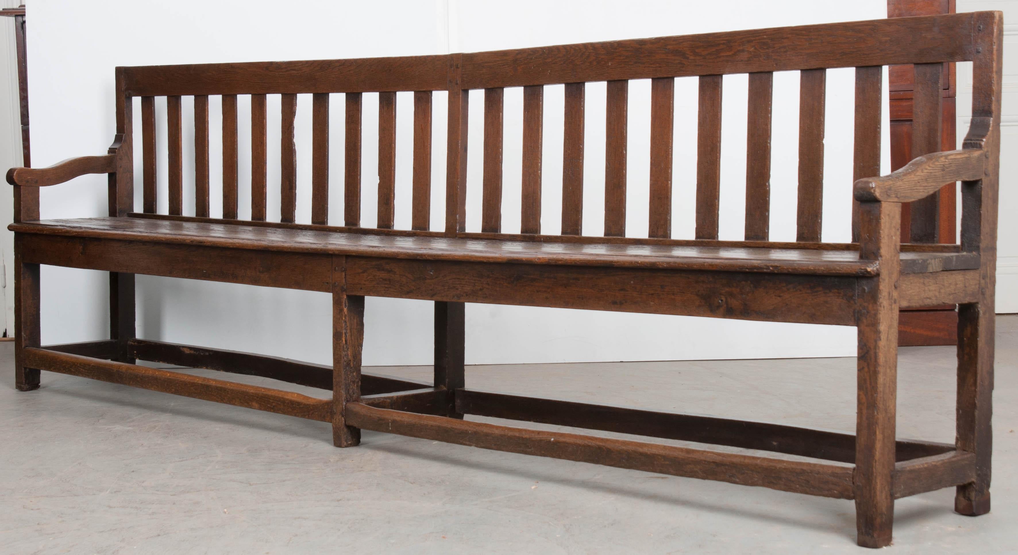 A lengthy oak bench, made in France circa 1880. The antique was designed with functionality in mind, but over the years has become a beautiful piece of furniture. The back is formed with spaced slats to support the back and a long, flat seat. The