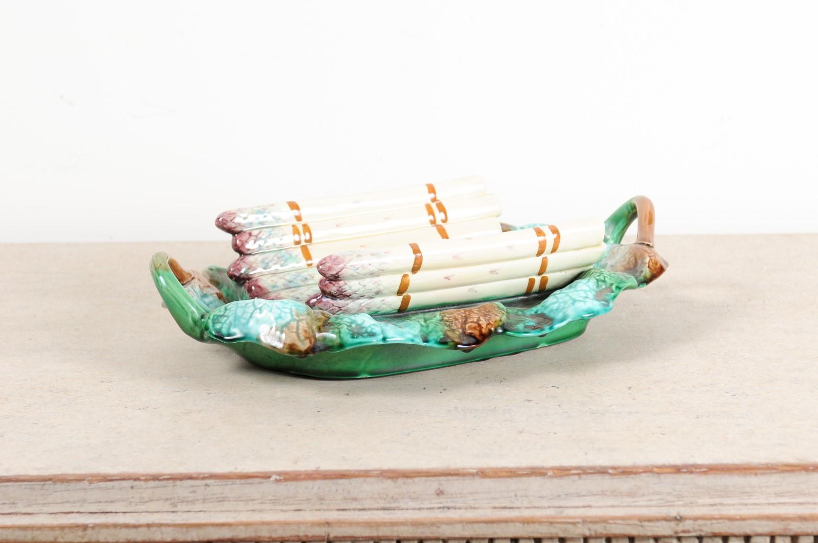A French Longchamp Majolica asparagus server from the 19th century, with green, purple and brown tones. Created in France during the 19th century, this Majolica server features a curving cradle adorned with purple and cream colored asparagus. The