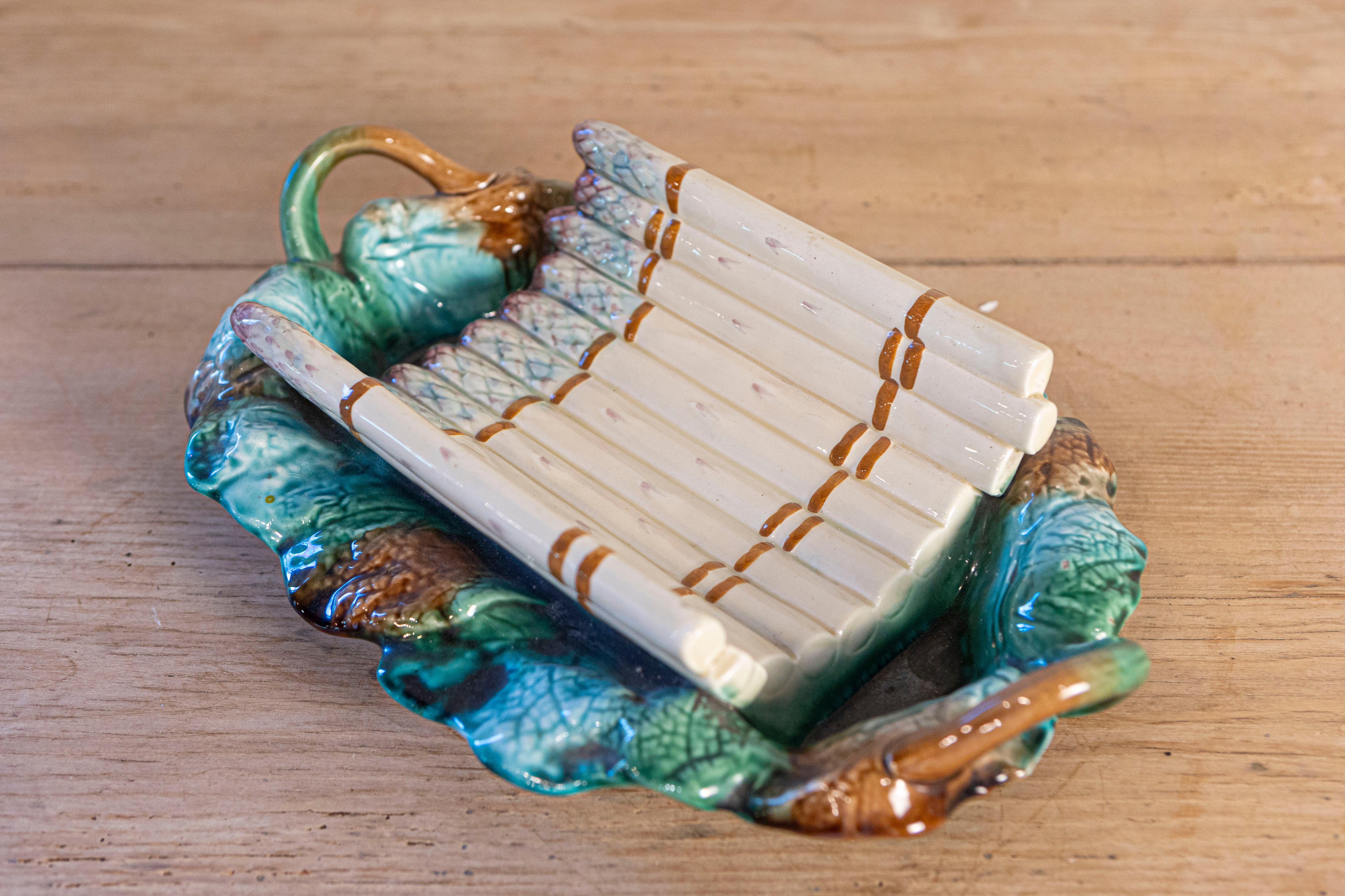 Un server per asparagi in maiolica francese Longchamp del XIX secolo, con toni verdi, viola e marroni. Creato in Francia nel XIX secolo, questo server in maiolica presenta una culla curva ornata da asparagi color crema e viola. Il piatto ovale