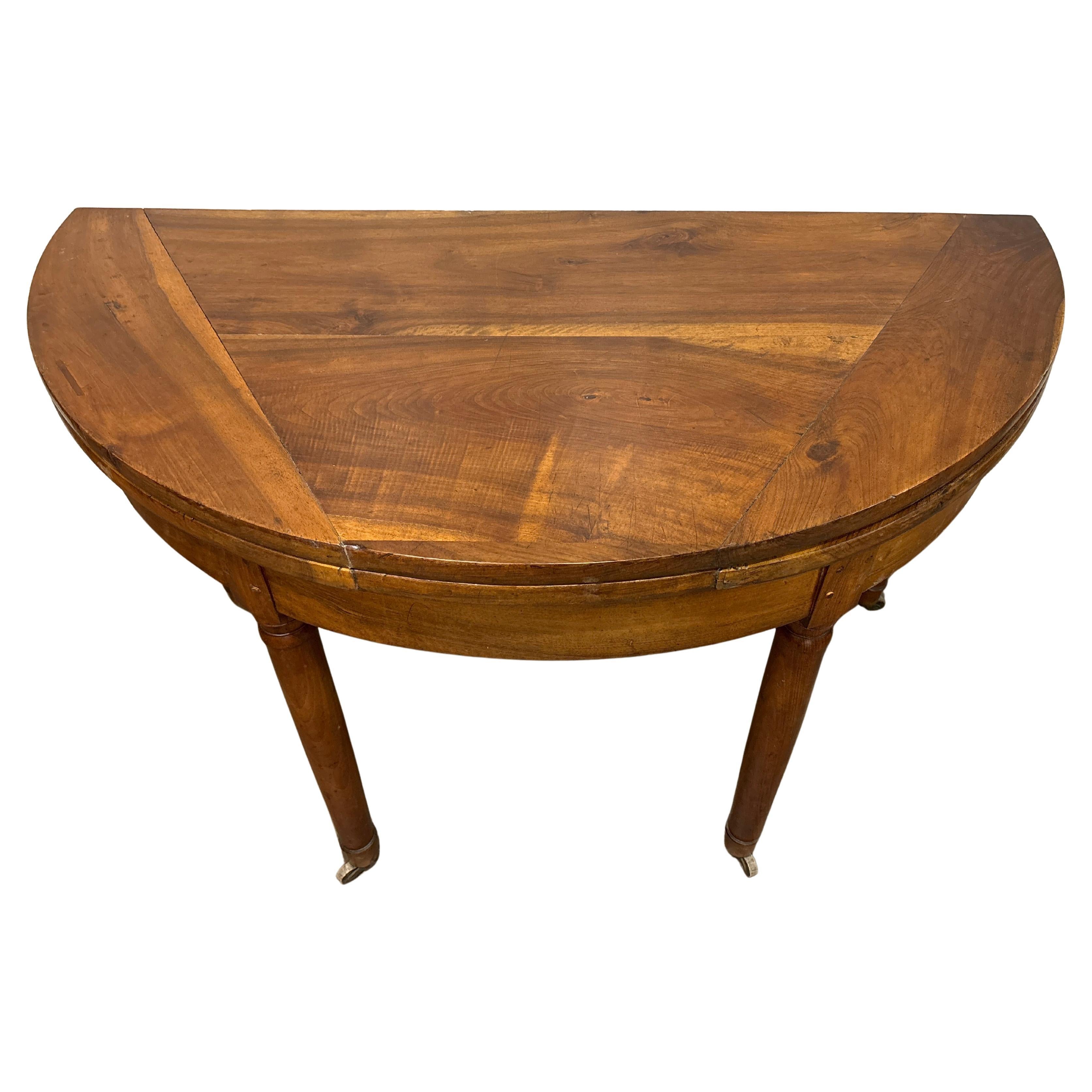 Cette table en demi-lune est fabriquée en noyer flammé et possède des rouleaux aux pieds. Elle peut également servir de table ronde et son diamètre est de 50,5