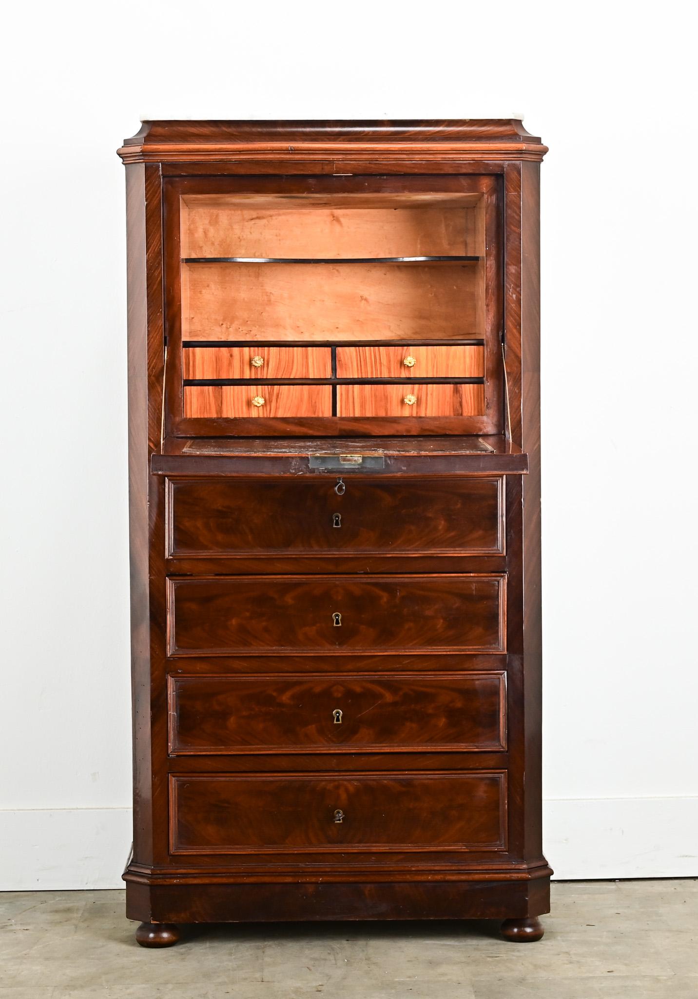 A French petite Louis Philippe secrétaire à abattant. Made of a beautifully figured bookmatched burl mahogany with its original white marble top. Three faux drawers at the top hide the drop down desk opening with its working lock and key to a fitted