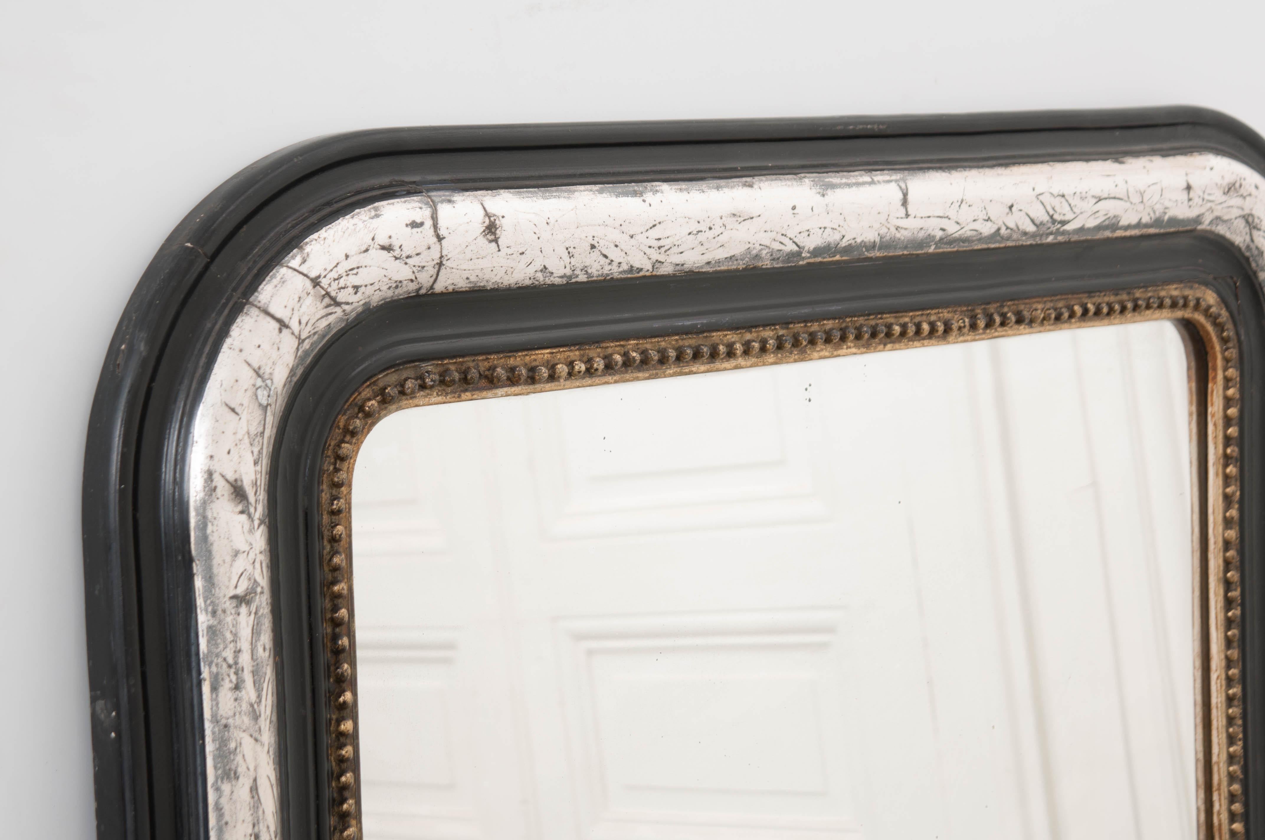 This fine period Louis Philippe ebonized and silvered mirror, circa 1840, is from France and has a fabulous patina. It features a gold-gilt beaded liner which makes it versatile enough to easily blend into any interior.