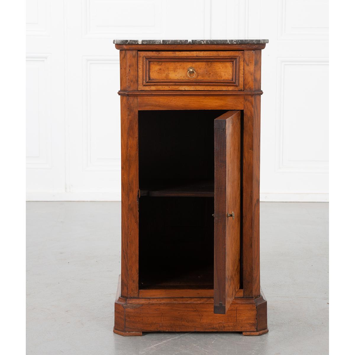 A fantastic French 19th century Louis Philippe bedside made with a burl walnut veneer front. The antique has a Saint-Anne marble top that is set over a panel drawer with a loop brass pull and the door below with an oval brass pull. All sit on a