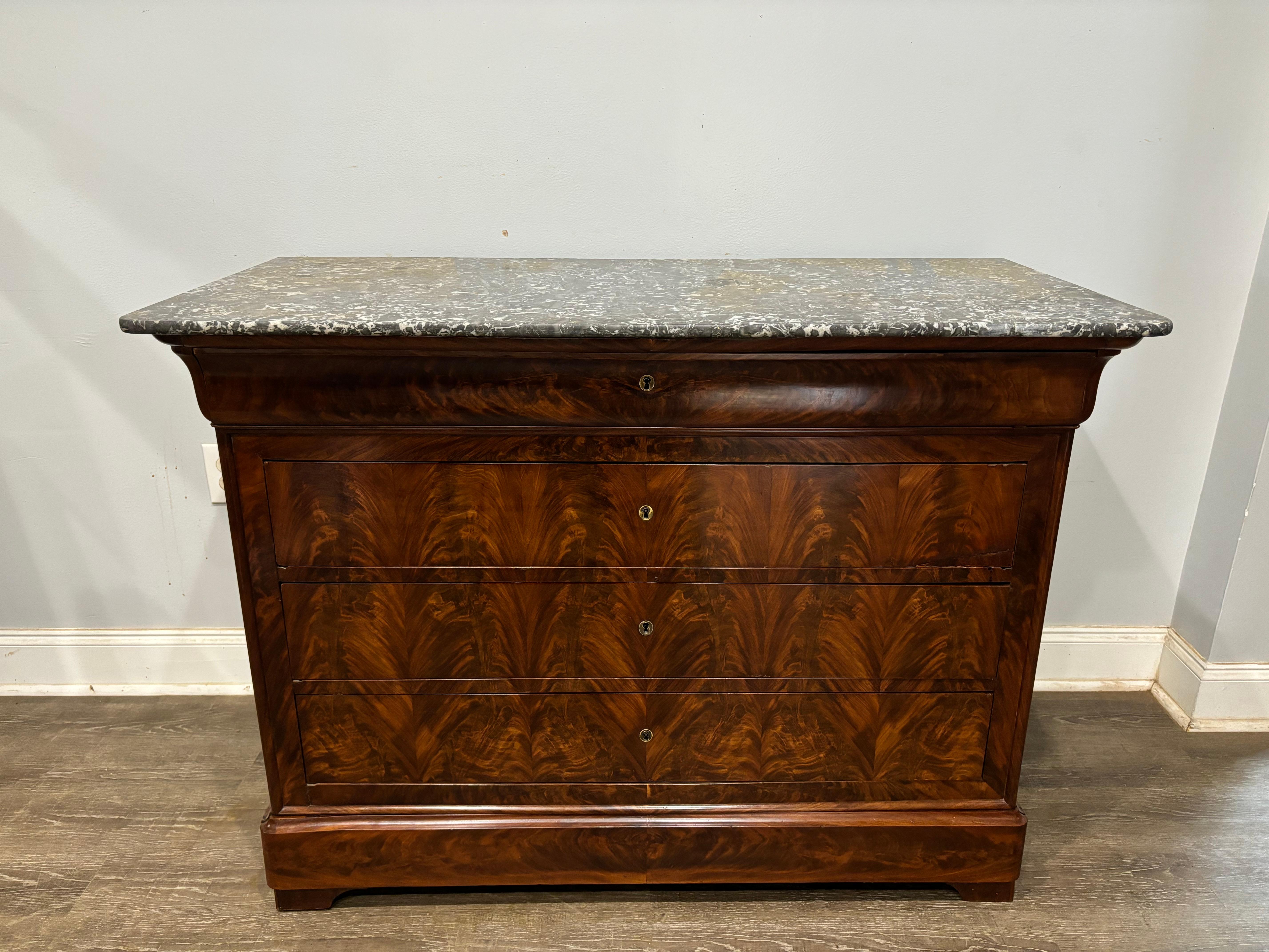 This Louis-Philippe French Commode is made of flamed mahogany with a Saint-Anne marble top. it has 5 drawers.