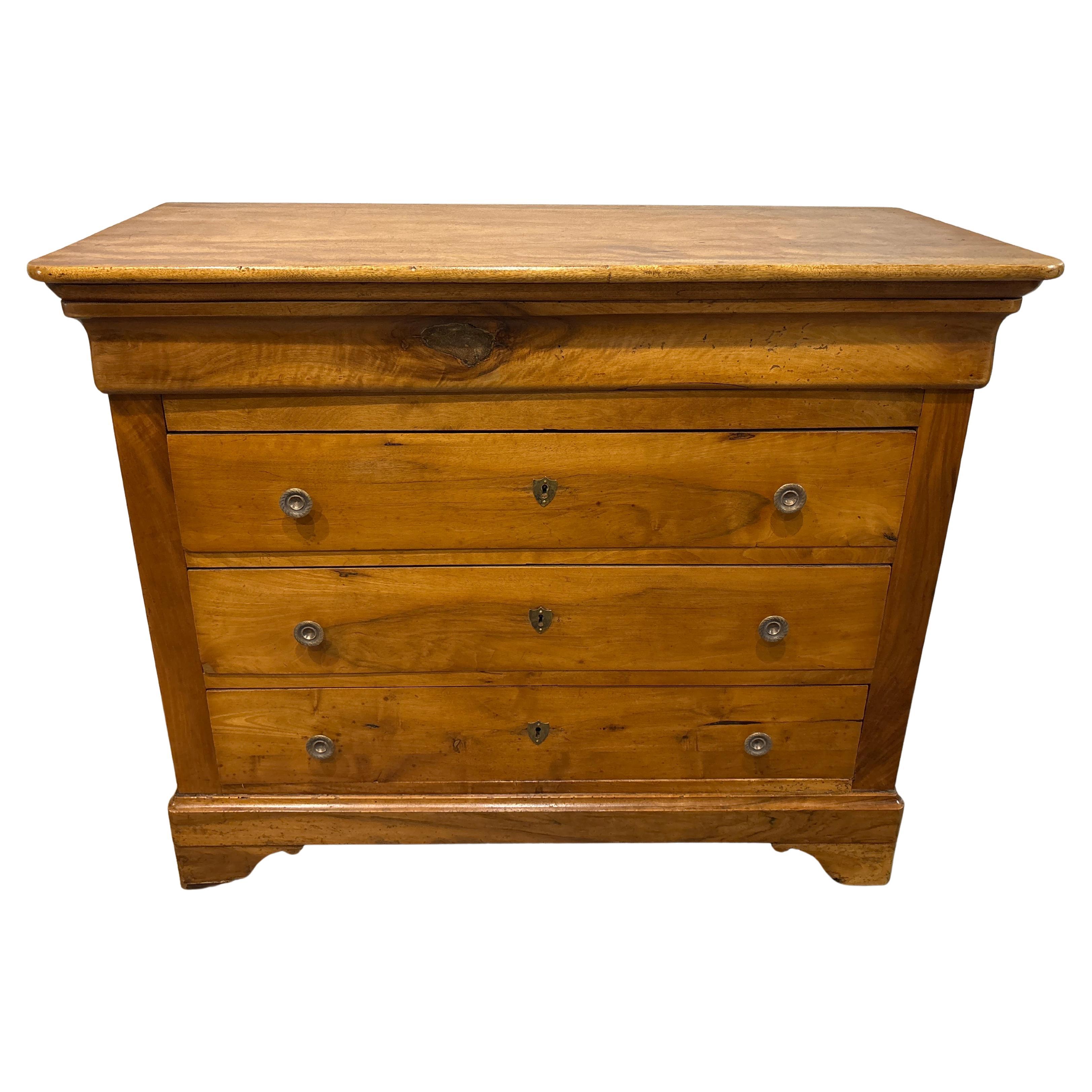 Cette commode Louis-Philippe est en noyer flammé uni. Sur le tiroir du haut, vous pouvez remarquer le point central de l'encoche de l'arbre.