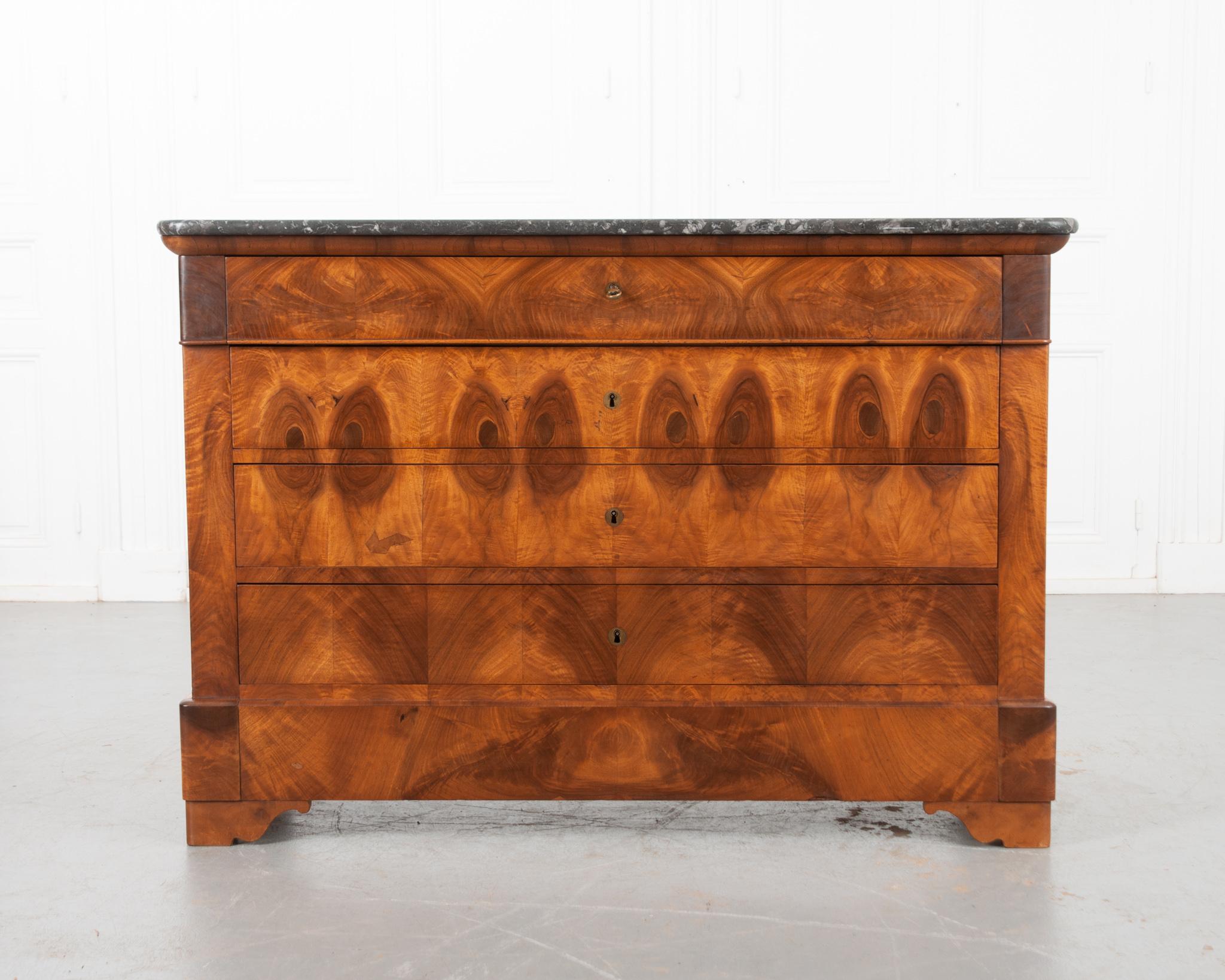 A classic Louis Philippe-styled four-drawer mahogany commode from 19th century France. The case antique has a beautiful gray marble top, with rounded front corners to match the base. The apron contains a hidden lockable drawer. The three