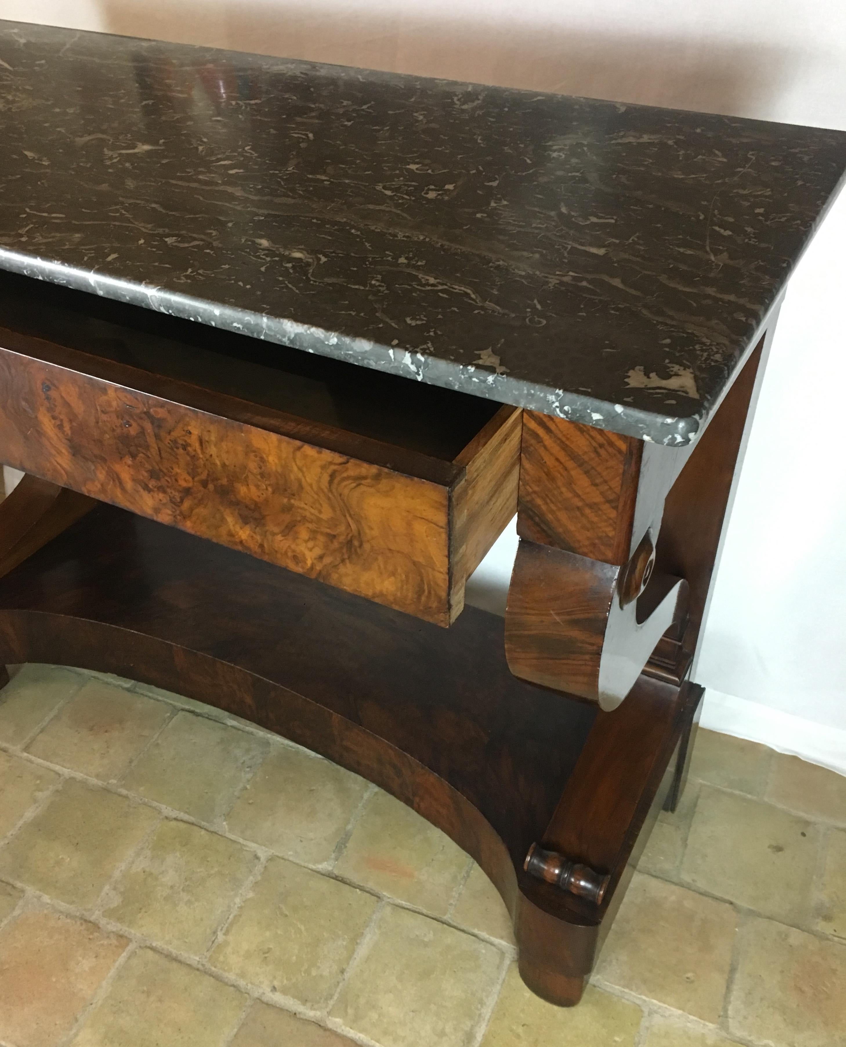 A 19th century French flamed walnut Louis-Philippe/Restoration period console table with a rectangular variegated grey marble top and pull-out drawer. 

This elegant piece rests on tapered front legs and straight rear legs joined by a rectangular