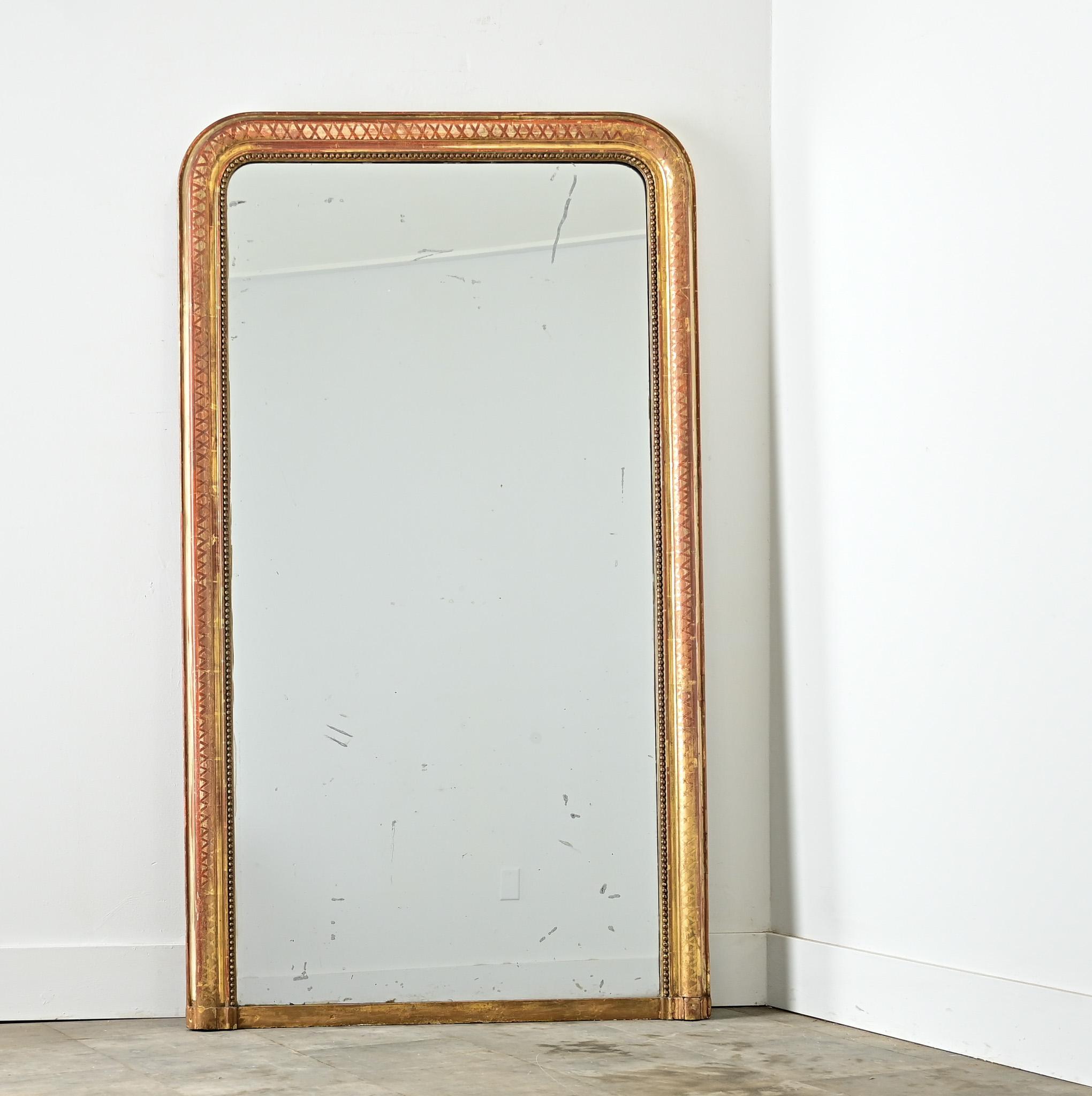 Un spectaculaire miroir de cheminée Louis Philippe du 19ème siècle, doré à l'or fin, dont la glace d'origine révèle de curieuses taches de rousseur. La moulure incorpore un subtil motif en treillis, dont la définition est nuancée par le substrat