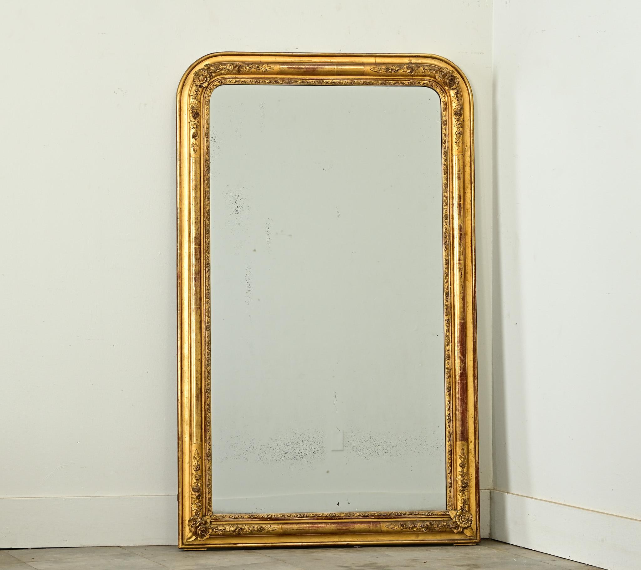 A sumptuous and intricately carved French 19th Century Louis Philippe style giltwood mirror. This amazing, hand-crafted frame takes the Louis Philippe-signature arched shape and embellishes upon it with three-dimensional floral motifs stationed at