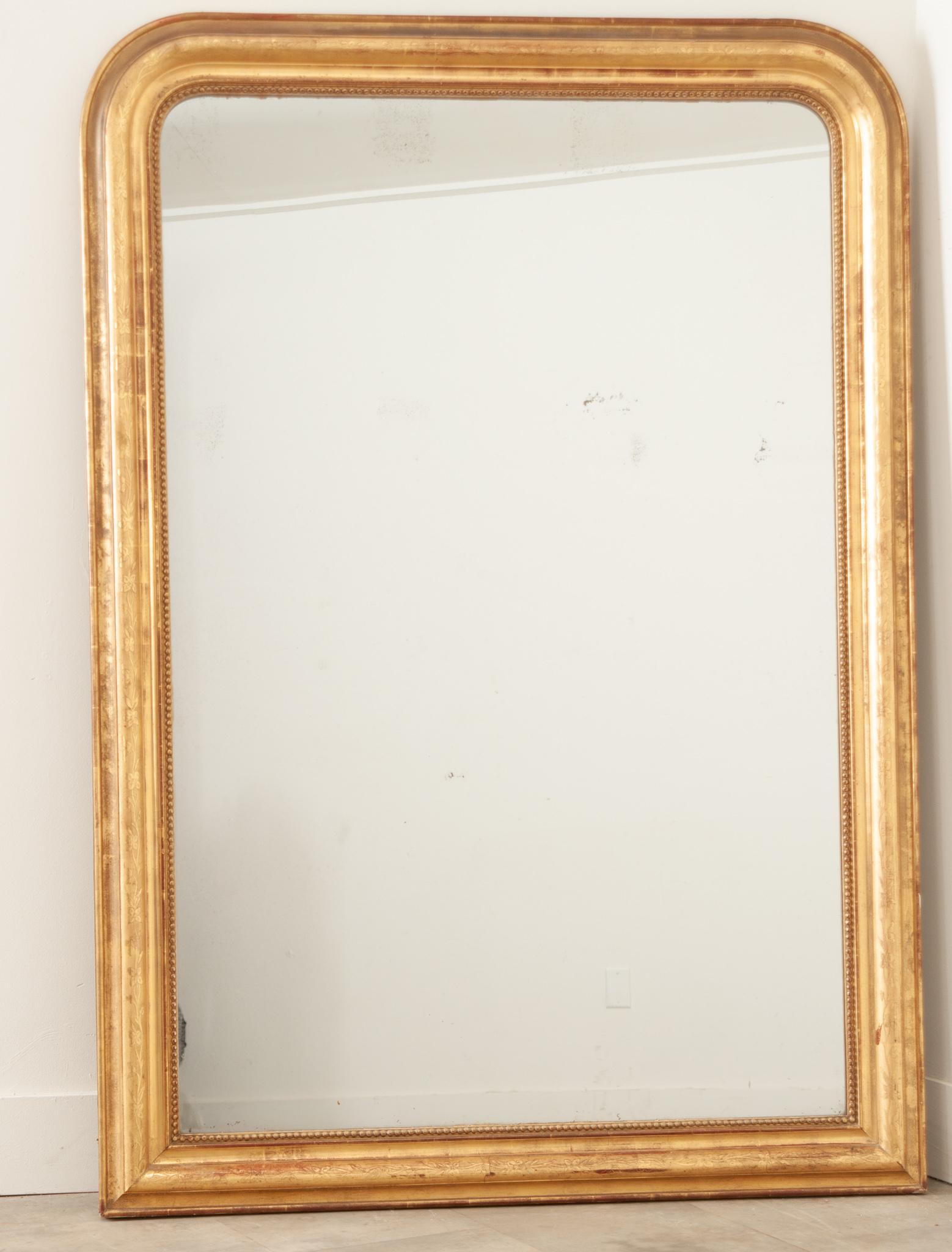 Miroir mural ou de cheminée de style Louis Philippe, élégant et intemporel avec son cadre rectangulaire profondément mouluré et garni, aux angles supérieurs arrondis. Fabriqué à la main en France au XIXe siècle, ce ravissant miroir présente des