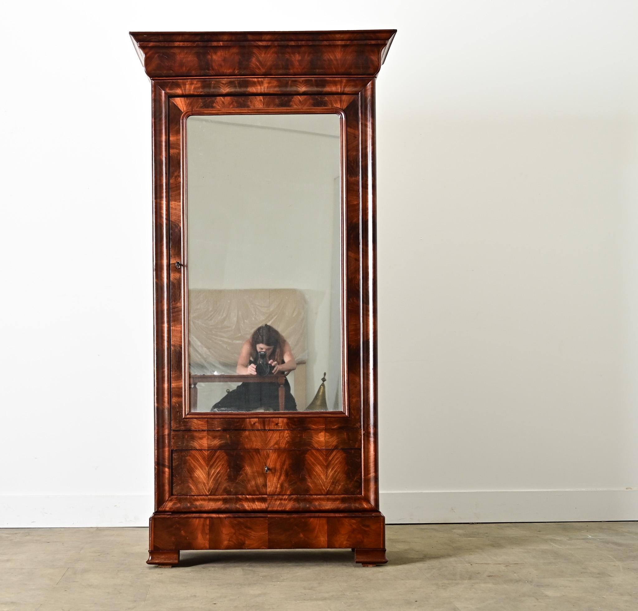 Dieser französische Schrank aus der Louis-Philippe-Periode (um 1840) ist von bescheidener Größe und langem Stil. Er ist aus geschnitztem und furniertem Mahagoni mit ausdrucksstarker Maserung und reicher Farbgebung gefertigt. Es nimmt die vertraute