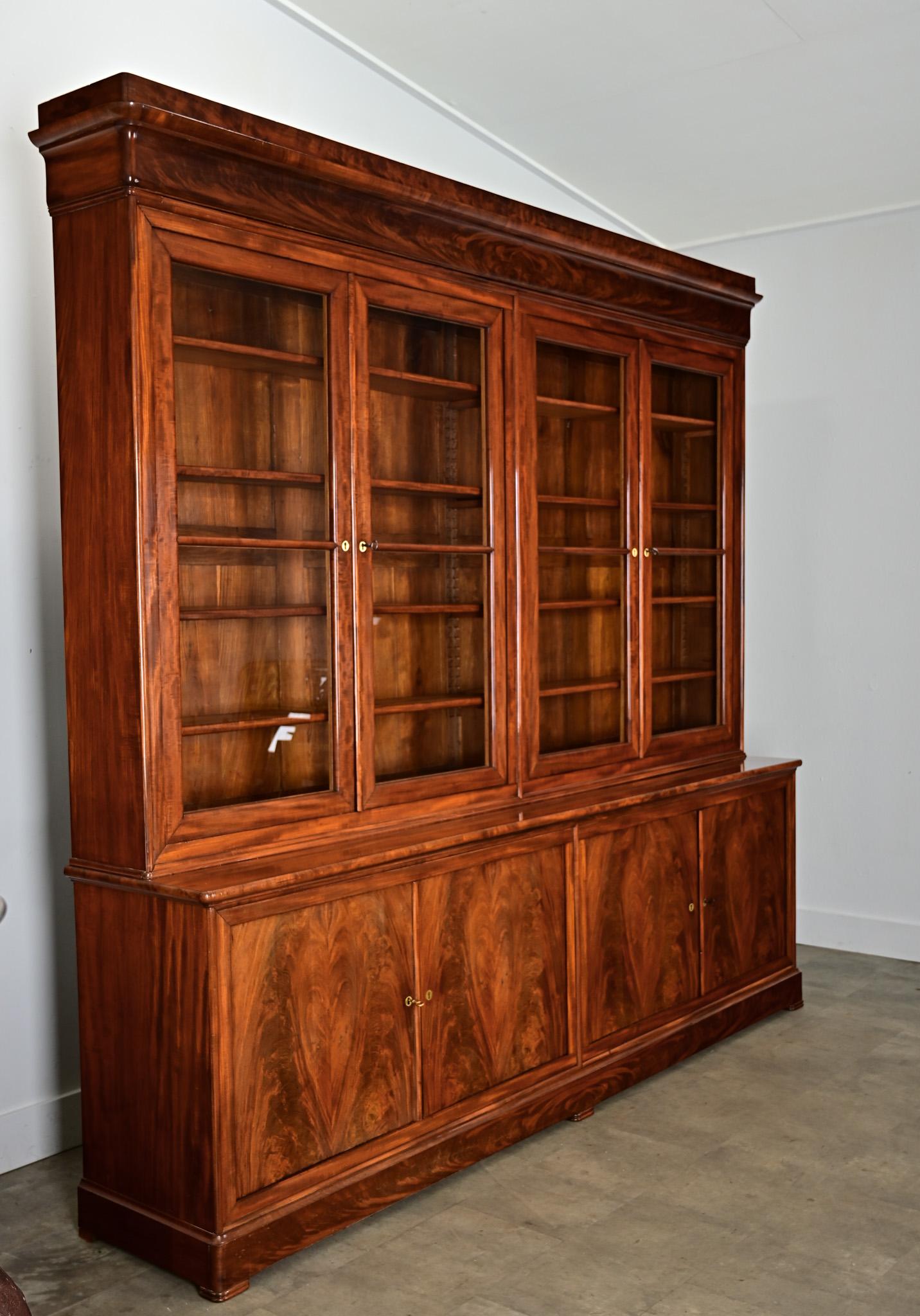 Une grande bibliothèque française du XIXe siècle de style Louis Philippe, fabriquée à la main en acajou, avec une rangée de quatre portes vitrées pour exposer des livres précieux, des objets de famille et d'autres collections dans un bureau ou une