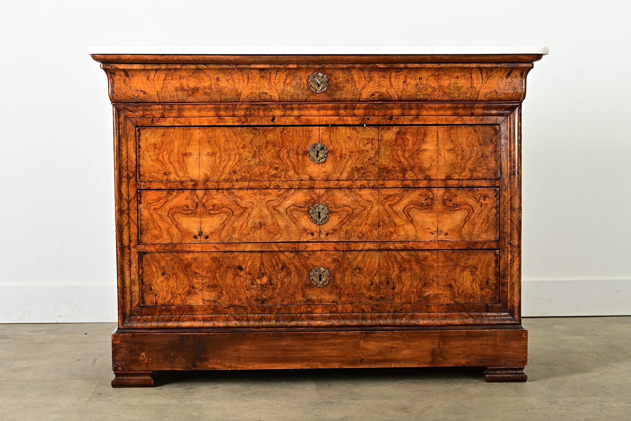 This Louis Philippe commode from France, 19th century, has mesmerizing burled, bookmatched walnut drawer fronts with dense ripples of grain pattern that flow from one to the other for a unified effect. On the top surface, the white marble shows thin