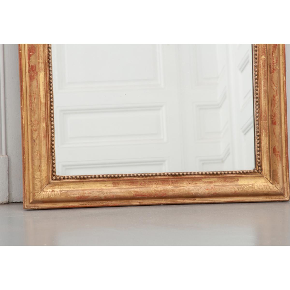 This fantastic gold gilt Louis Philippe-style mirror still features its original mirror plate. The frame has a finely detailed motif of flowers continuing around the whole and a carved pearl perimeter that runs along the mirror plate edge. Bold