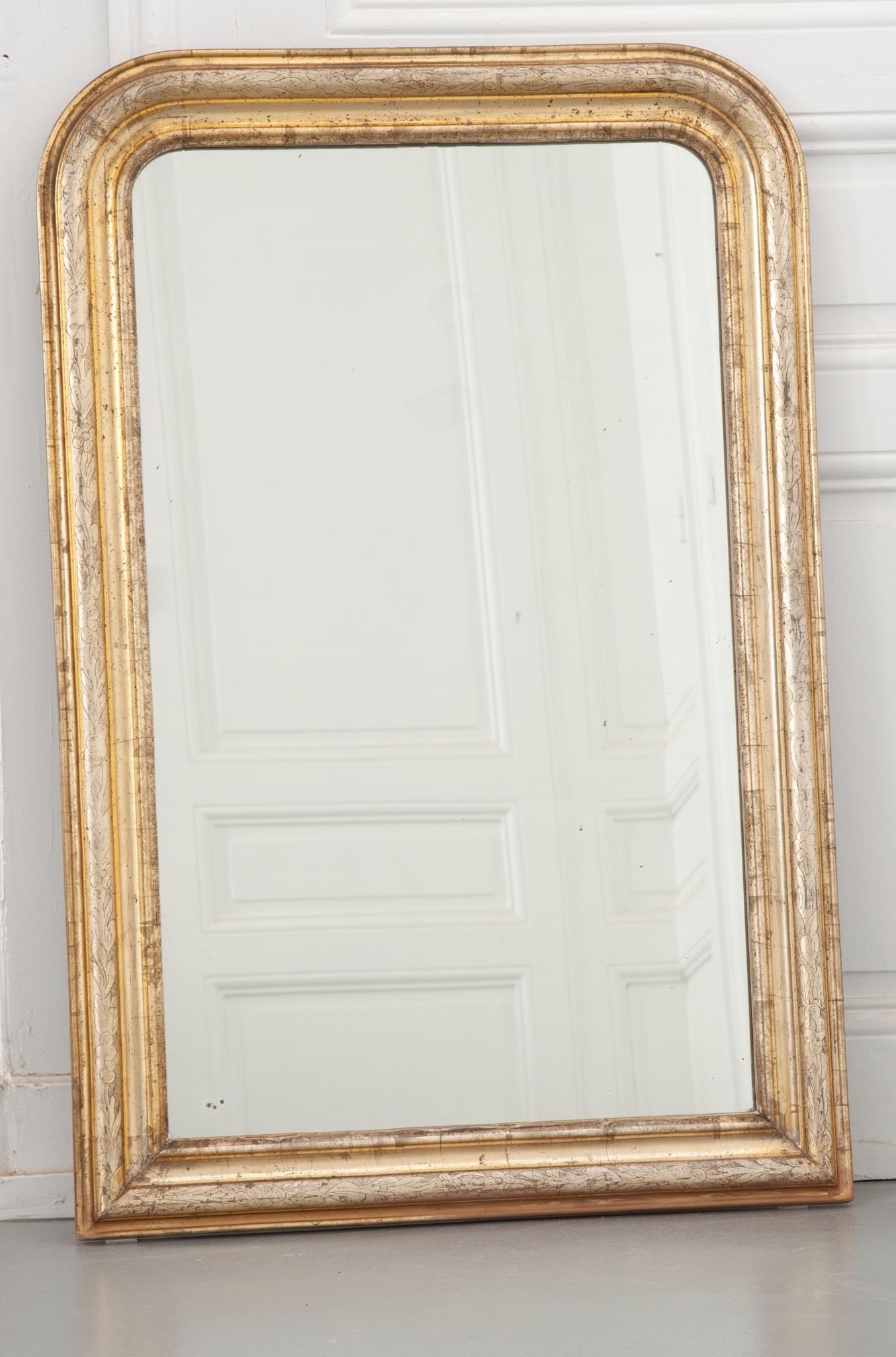 A fabulously patinated Louis Philippe style mirror. A delicate border of etched flowers surrounds the original mercury mirror plate with simple elegance. The contrast of gold and silver luster give this mirror a unique look. The original mirror