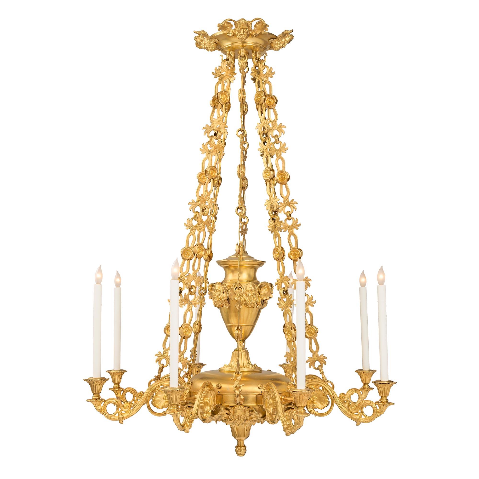 An impressive large-scale French 19th century Louis Philippe period ormolu eight-arm chandelier. The chandelier is centered by a bottom inverted finial with a mottled and foliate design. Below each arm are striking and finely detailed handsome faces