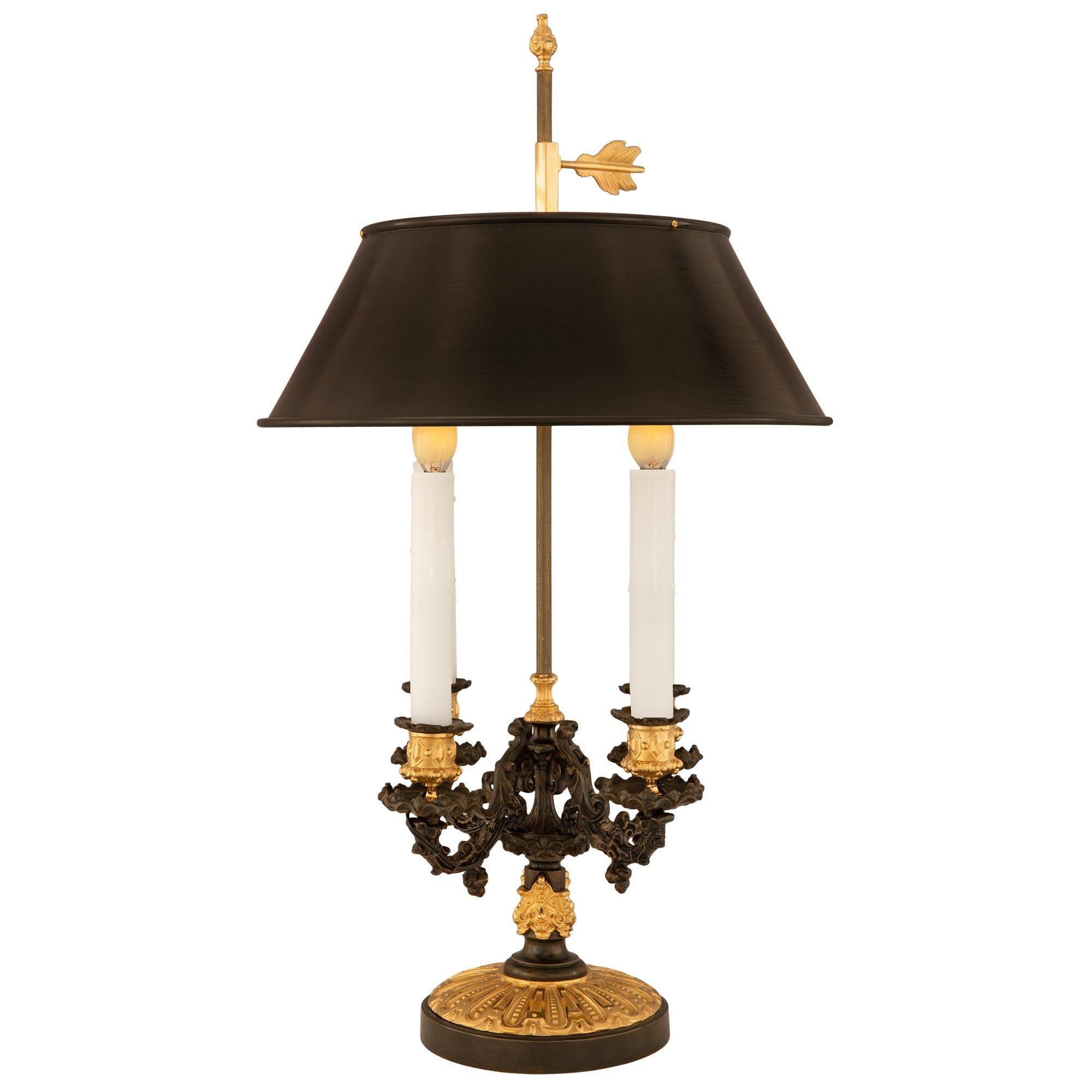 A striking French 19th century Louis Philippe period patinated bronze and ormolu bouillotte lamp. The four arm lamp is raised by an elegant circular patinated bronze base with beautiful foliate fluted designs in a superb satin and burnished finish.