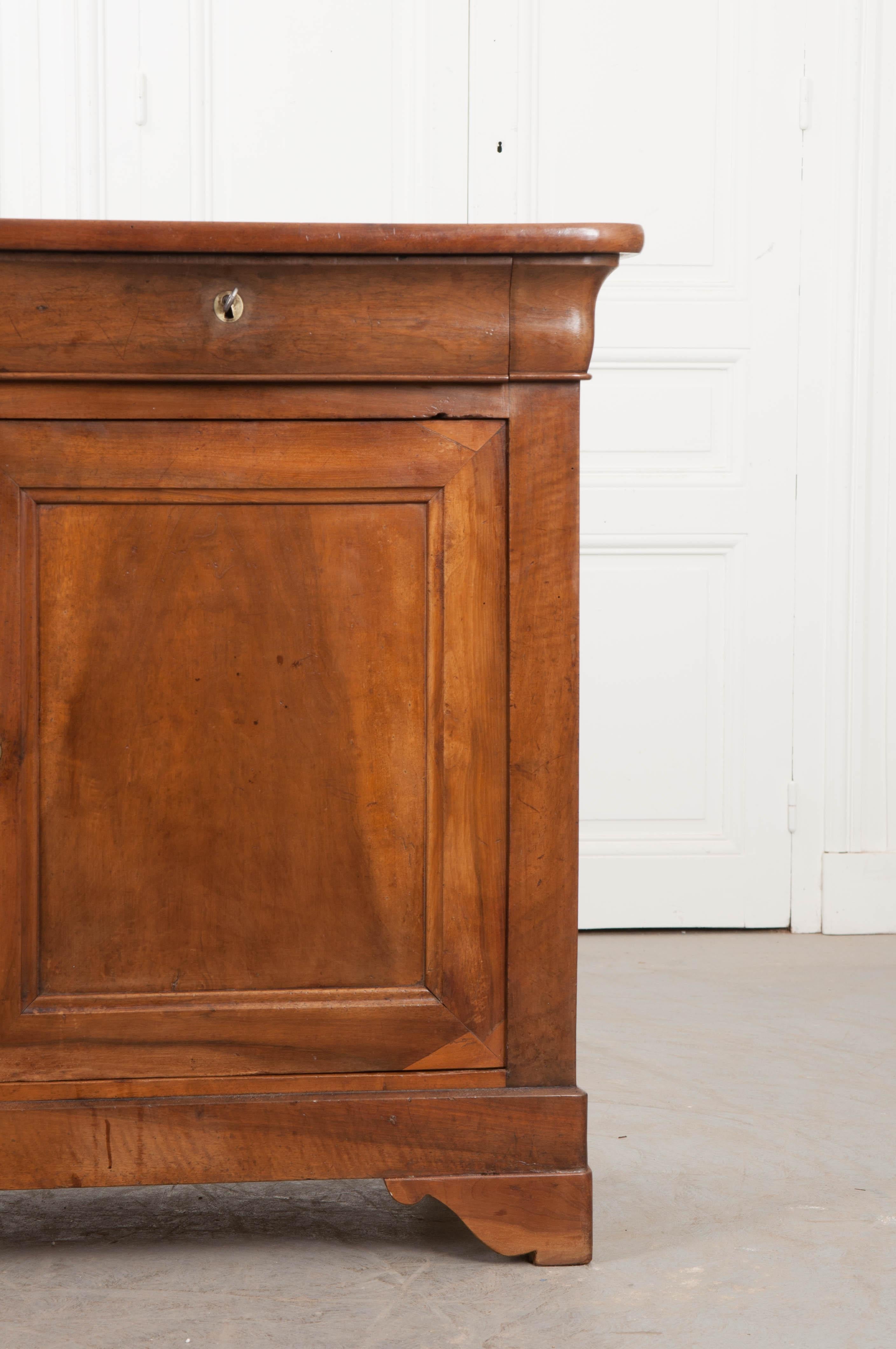 This beautiful period Louis Philippe walnut buffet, circa 1850, was found in France and boasts a gorgeous patina from years of proper French polishing. The walnut surface with rounded corners sits above a pair of apron drawers and a case with