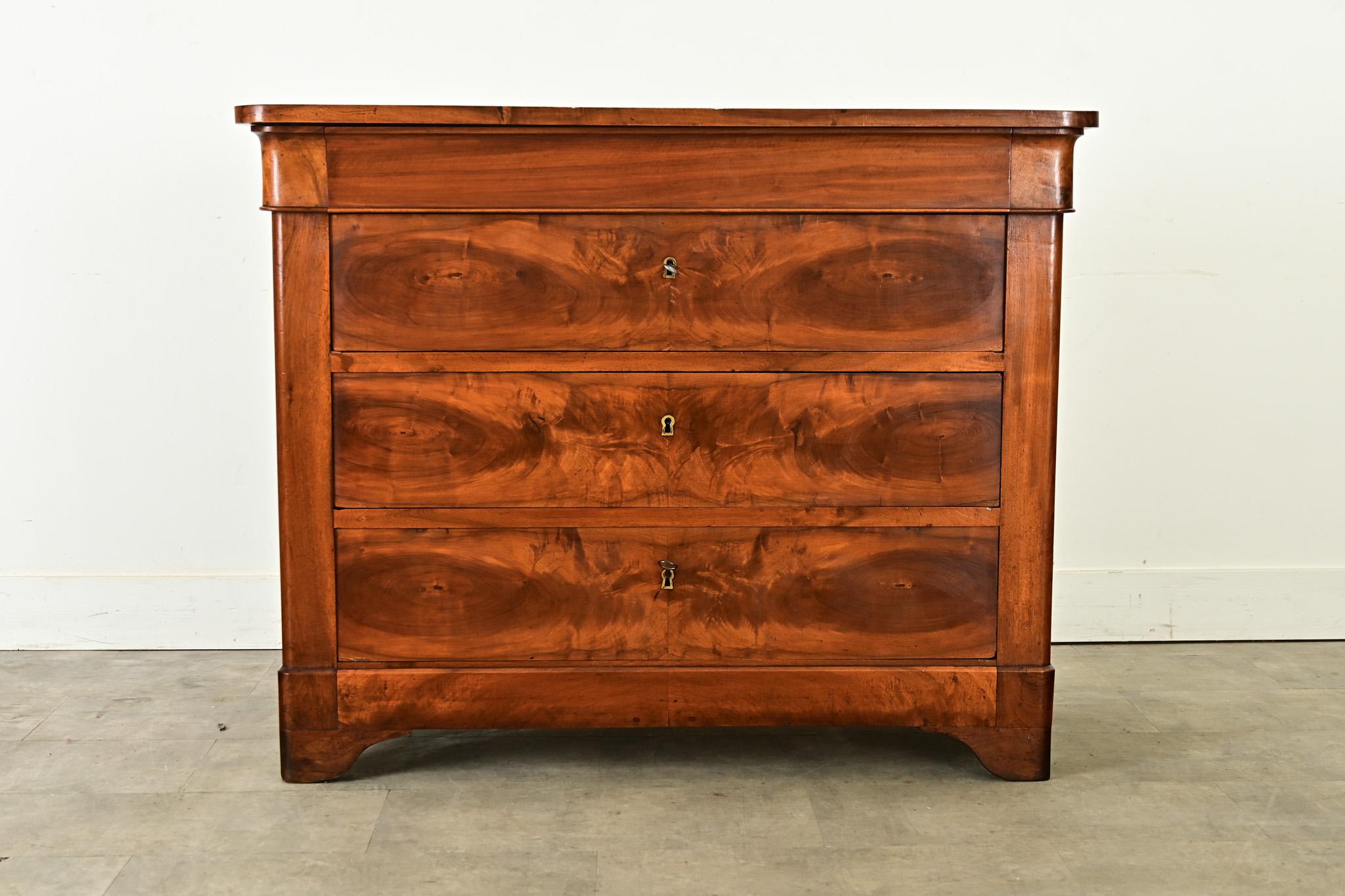 Splendida commode in noce di Phillip Lowe del XIX secolo, caratterizzata da un'eccezionale impiallacciatura a libro sui tre frontali dei cassetti inferiori. Questa graziosa commode presenta proporzioni forti e angoli arrotondati per organizzare la