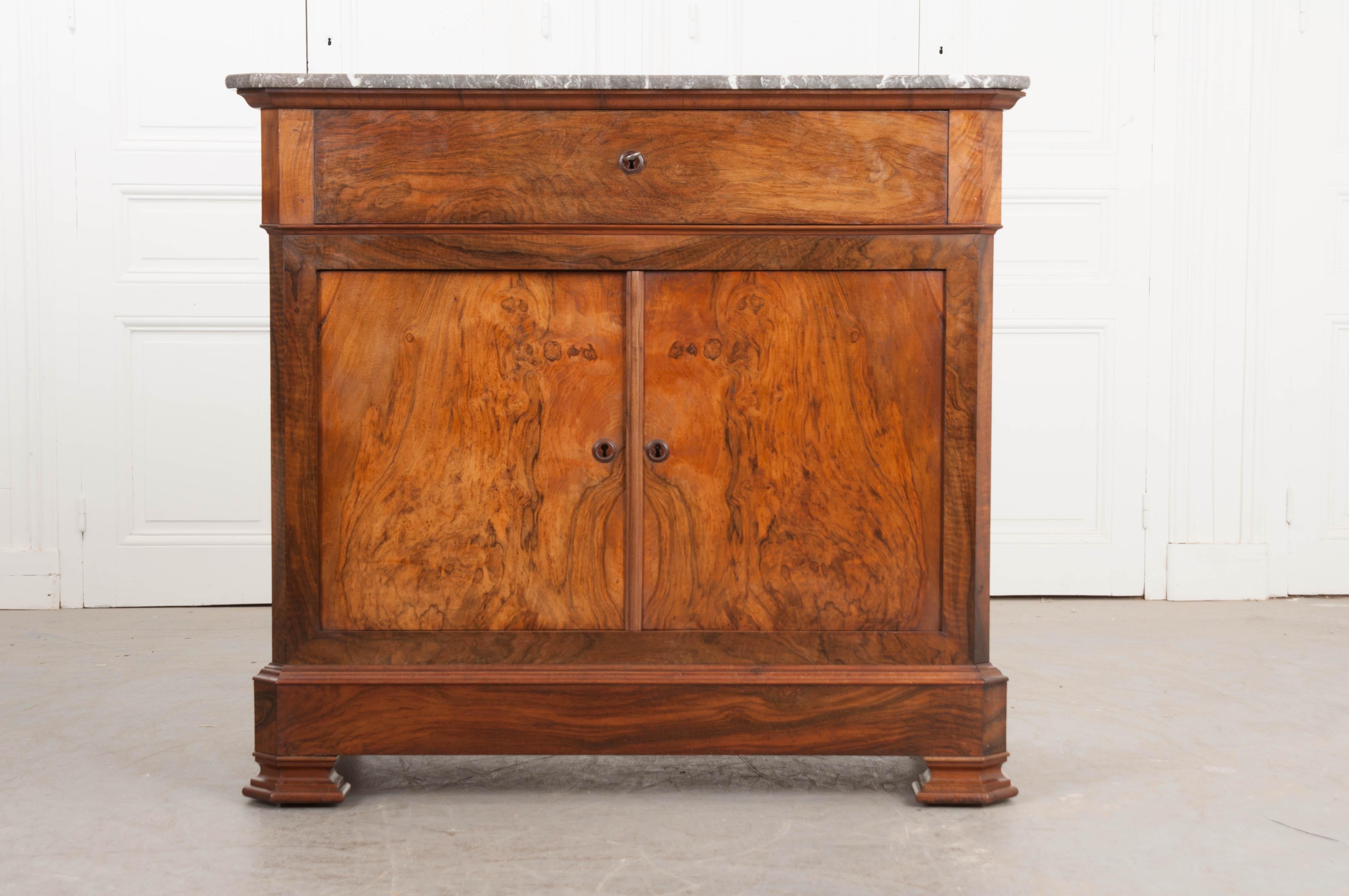 This handsome Louis Philippe marble-top walnut desk, circa 1830s is from France and features charcoal-grey marble with white veining and canted corners over a fall-front apron door which slides open to reveal a leather writing surface and four