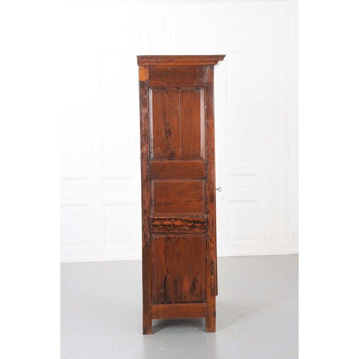 Gorgeous walnut bonnetiere with a geometric carved and paneled door on barrel hinges. All hand-pegged construction with original hardware. A single key works the lock and acts as the pull. Each side is comprised of three raised panels. The interior