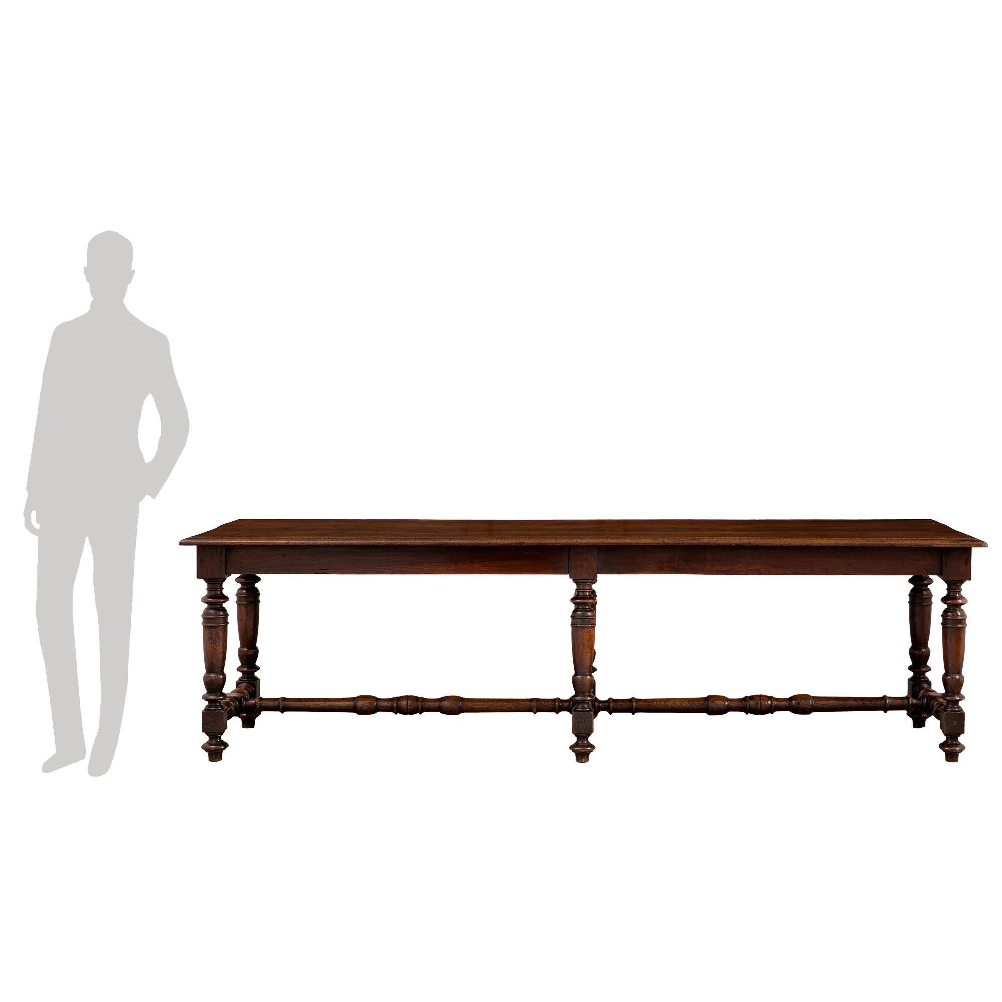 A handsome Country French 19th century Louis XIII style oak dining/center table. The table is raised by six elegant turned legs with topie shaped feet and striking block reserves which are each connected by a lovely turned stretcher. Above the