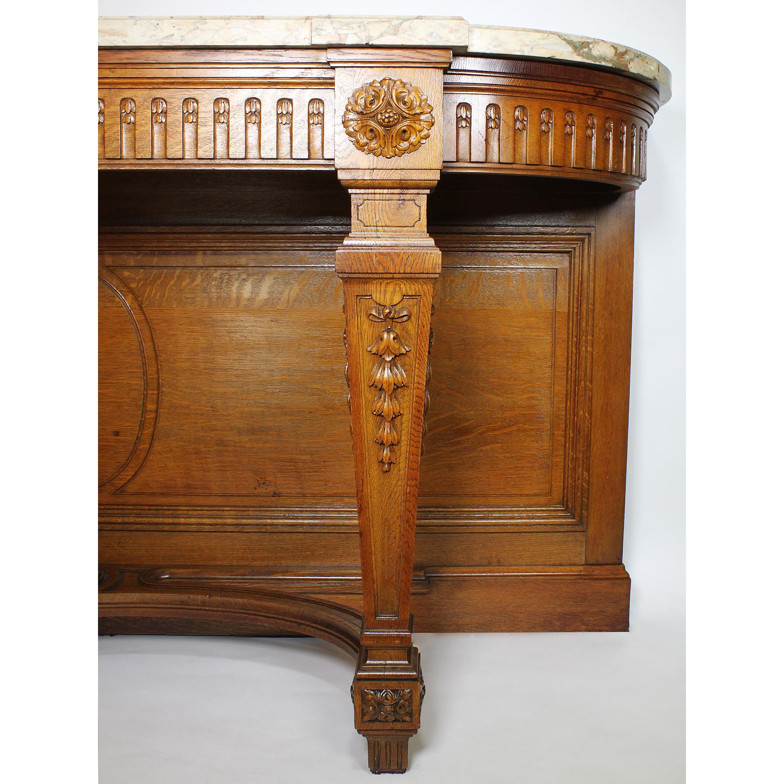 A large French 19th century Louis XIV style carved oak console or buffet with marble top. The tall and slender carved apron with serpentine sides raised with two front square-tapered legs centred with a carved rossette and floral design carvings on