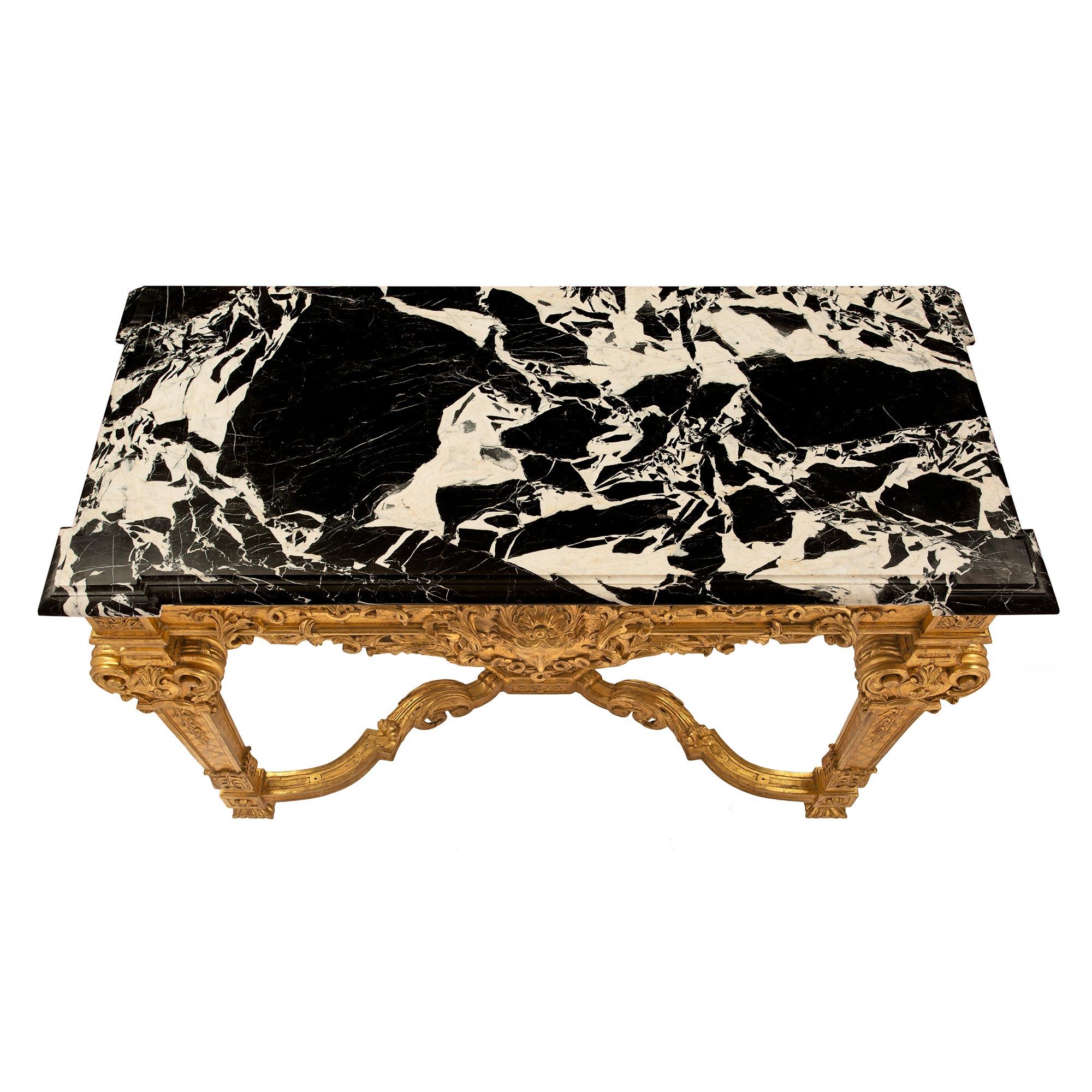 A stunning and large scale French 19th century Louis XIV st. giltwood and Grand Antique marble freestanding console. The console is raised by fine square foliate feet below block reserves, joined by a striking X shape stretcher. The stretcher