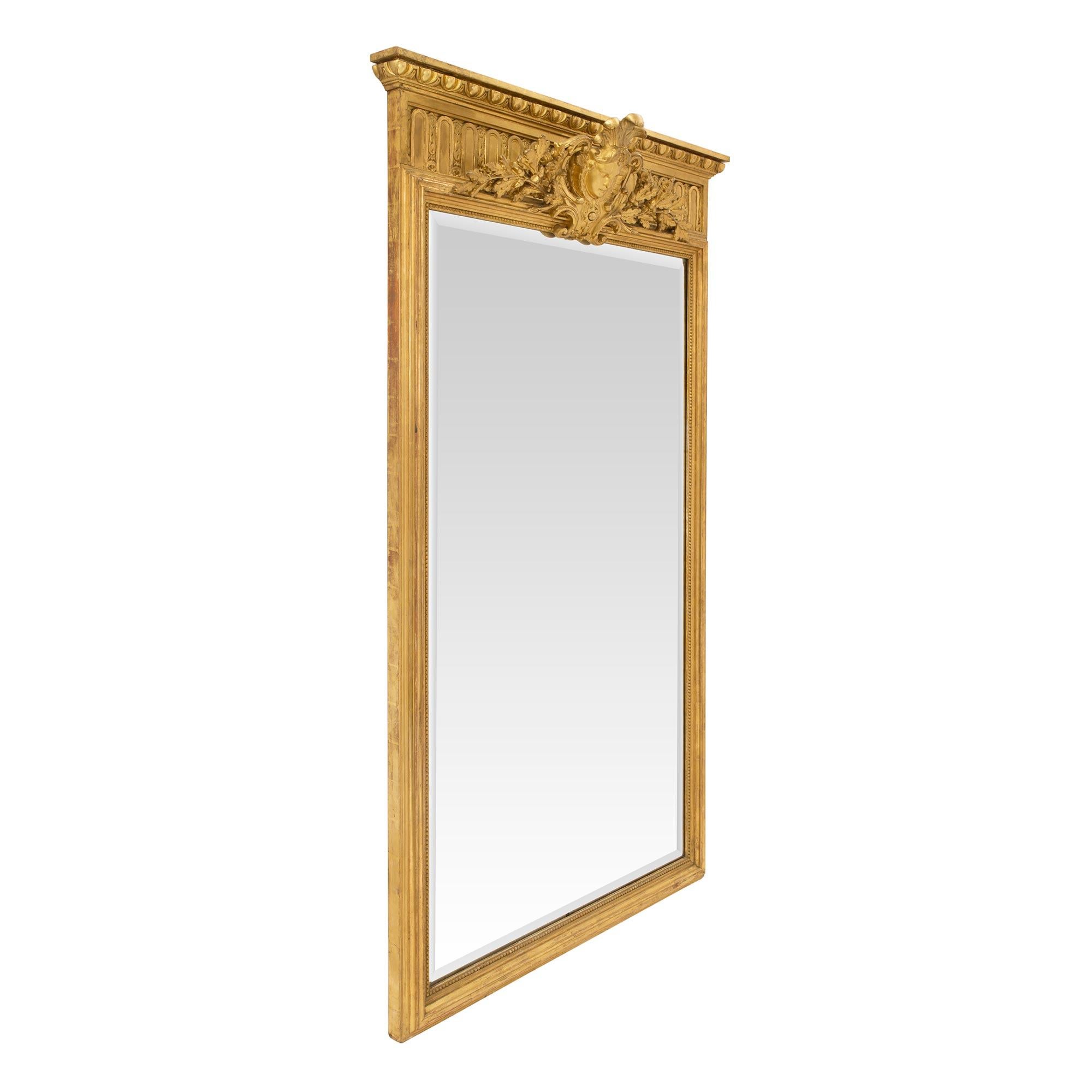 A handsome and powerful mid 19th century French Louis xiv st. Giltwood mirror. The Fluted sides and bottom with all original Watergilt burnished gold leaf balances a Wonderfully decorative carved top with The face of Louis XIV decorated with five